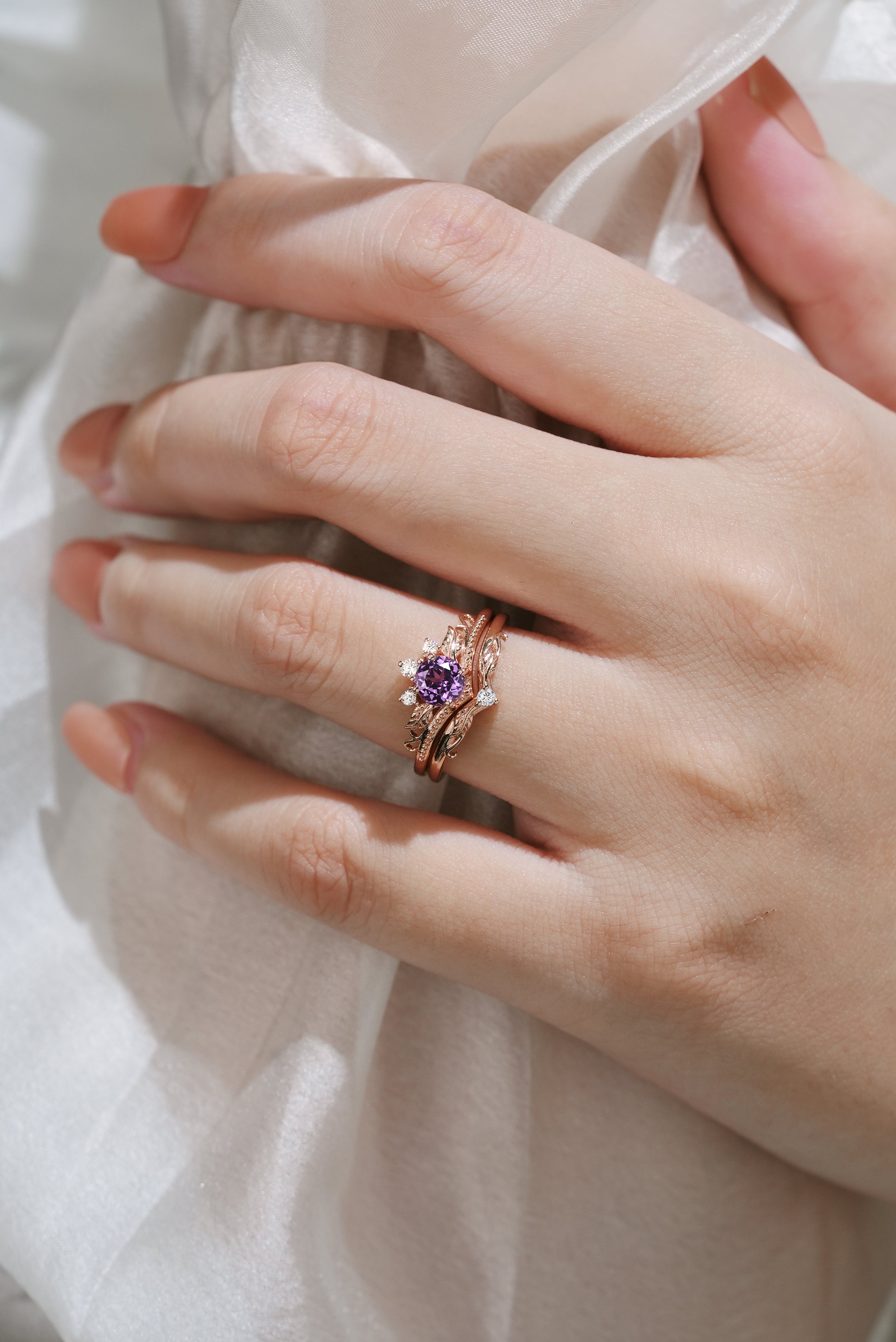 Hand wearing purple sapphire leaf engagement ring set