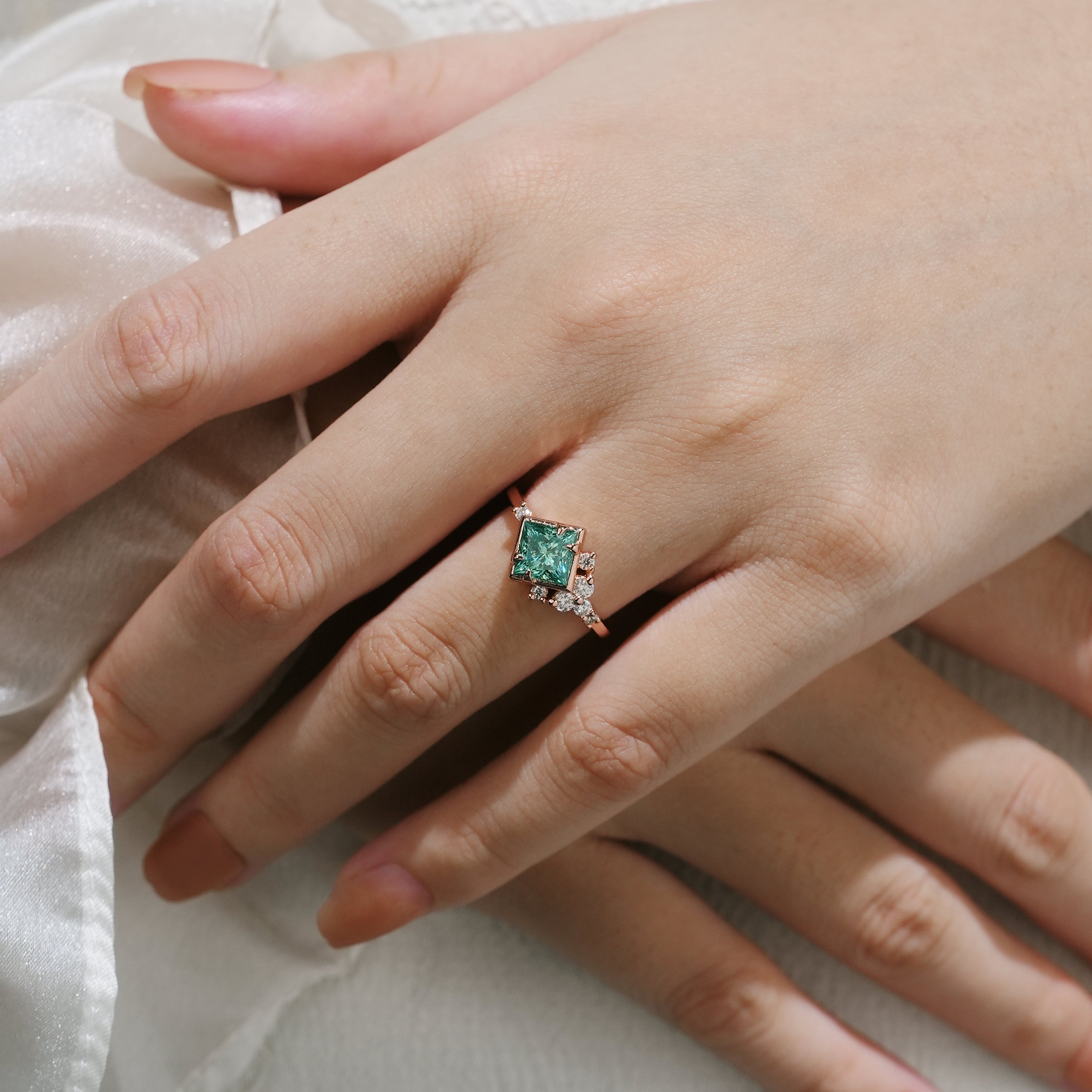 Hand wearing princess-cut green moissanite engagement ring, Lahela Jewelry