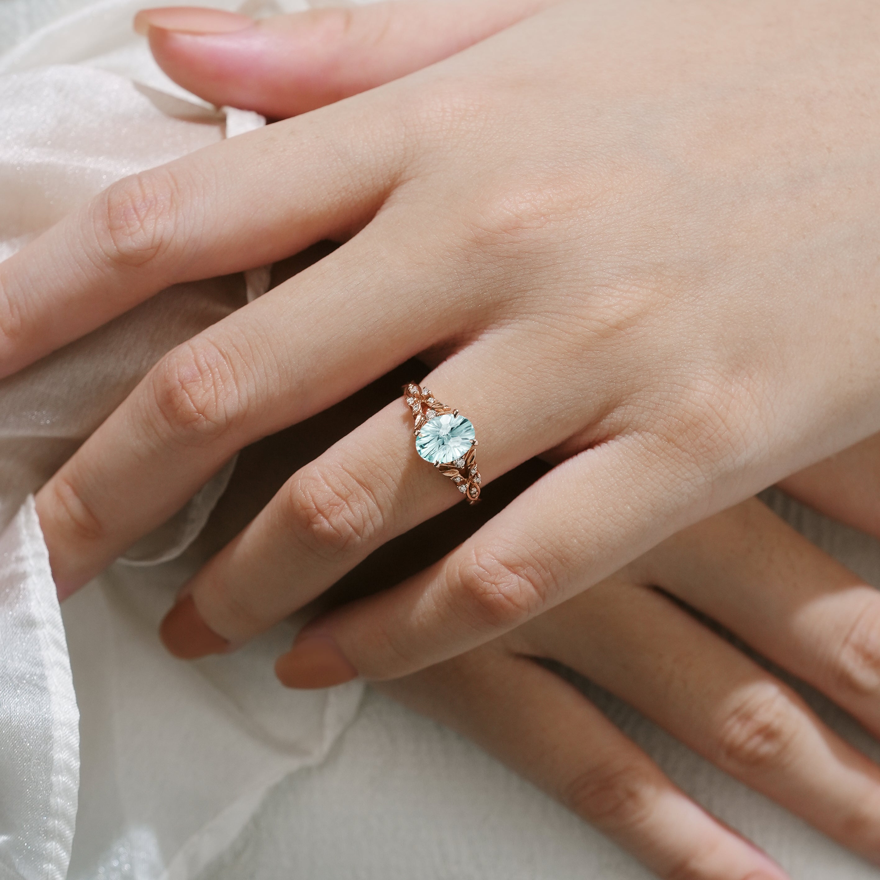 Oval aquamarine ring with leaf details on a hand