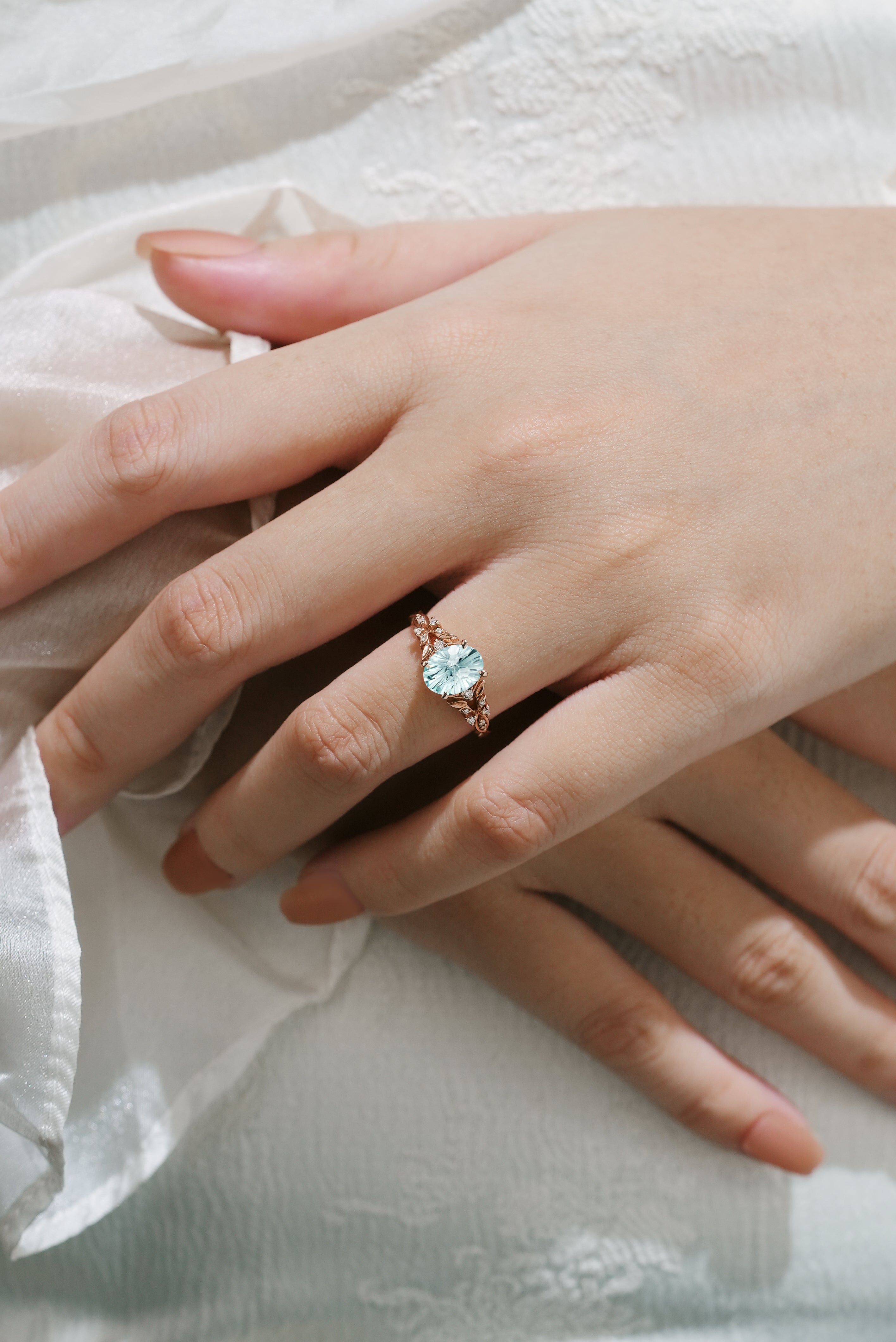 Oval aquamarine ring with leaf details on a hand