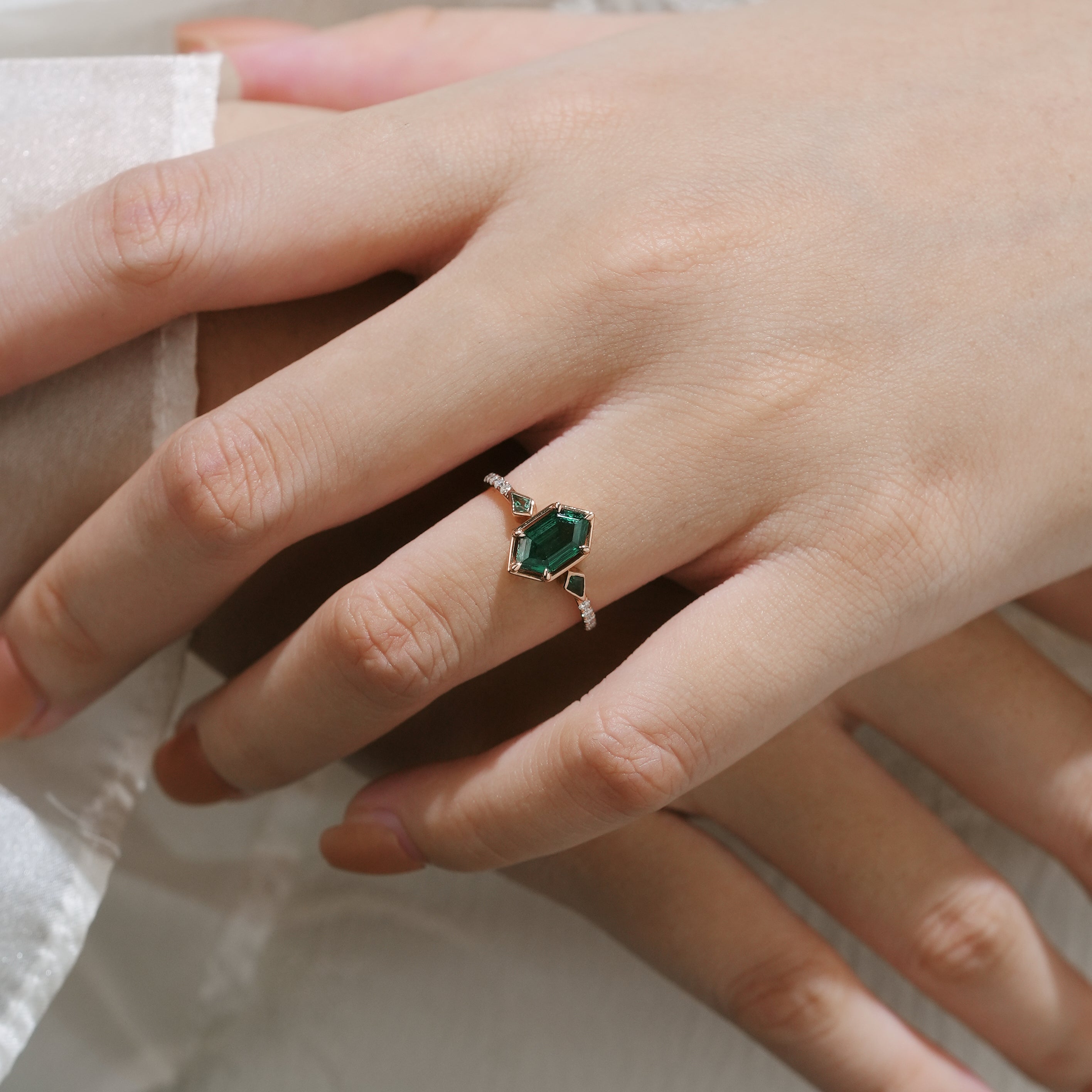 Woman's hand wearing emerald hexagon cut engagement ring