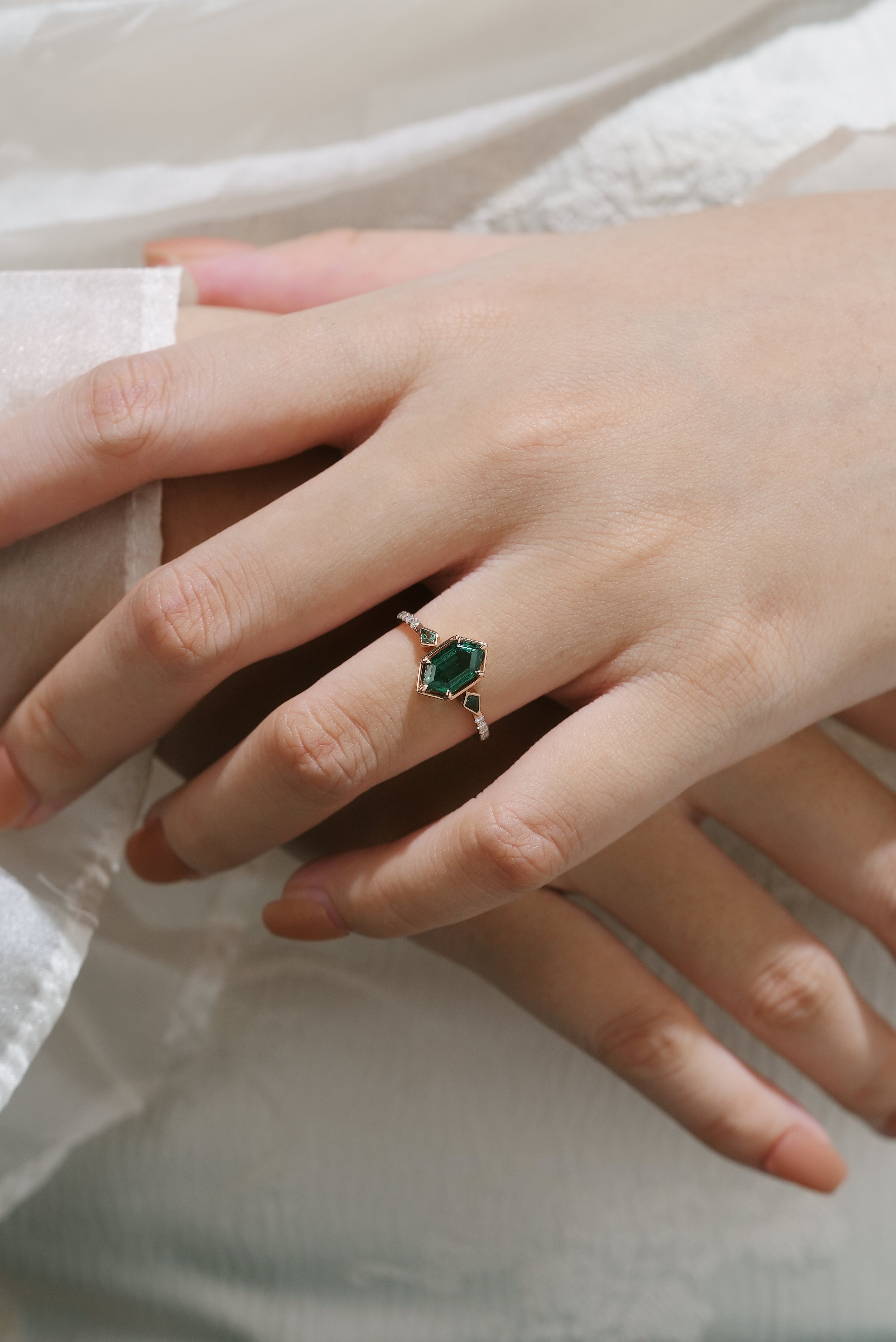 Woman's hand wearing emerald hexagon cut engagement ring