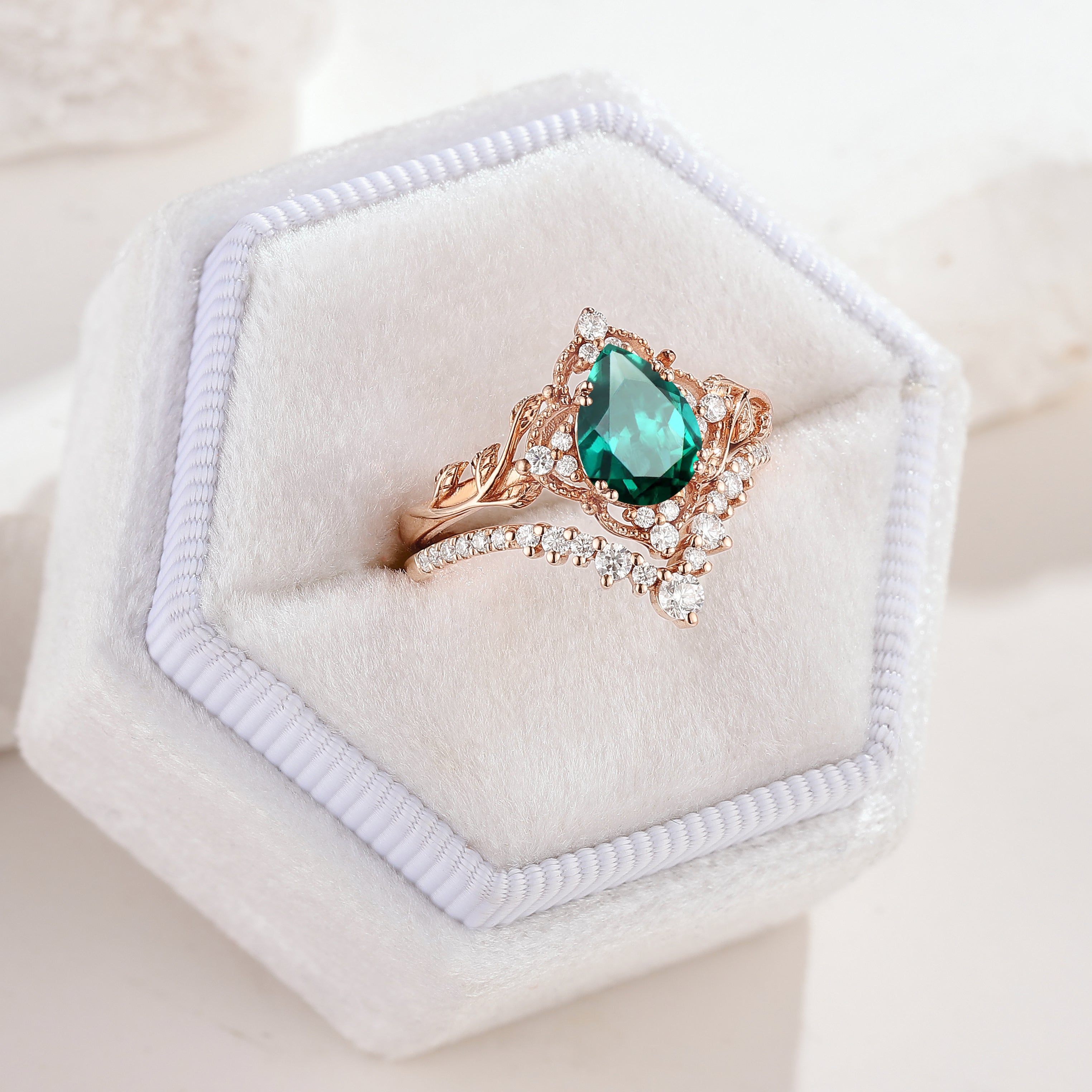 Rose gold leaf engagement ring set with pear-cut lab emerald and moissanite
