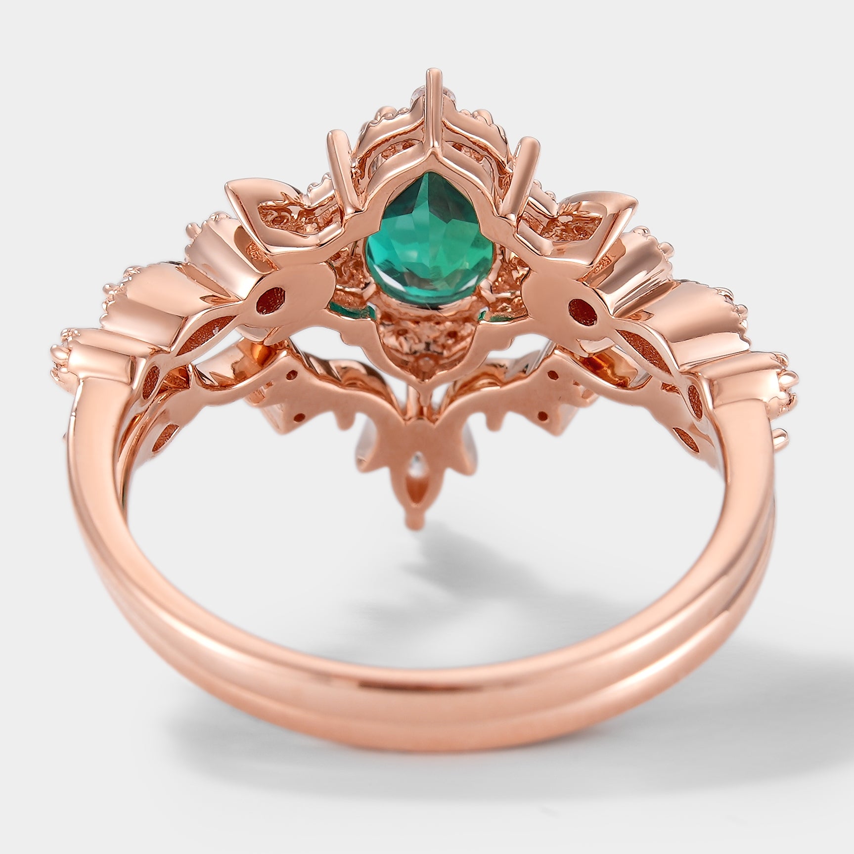 Rose gold emerald and moissanite engagement ring with floral design