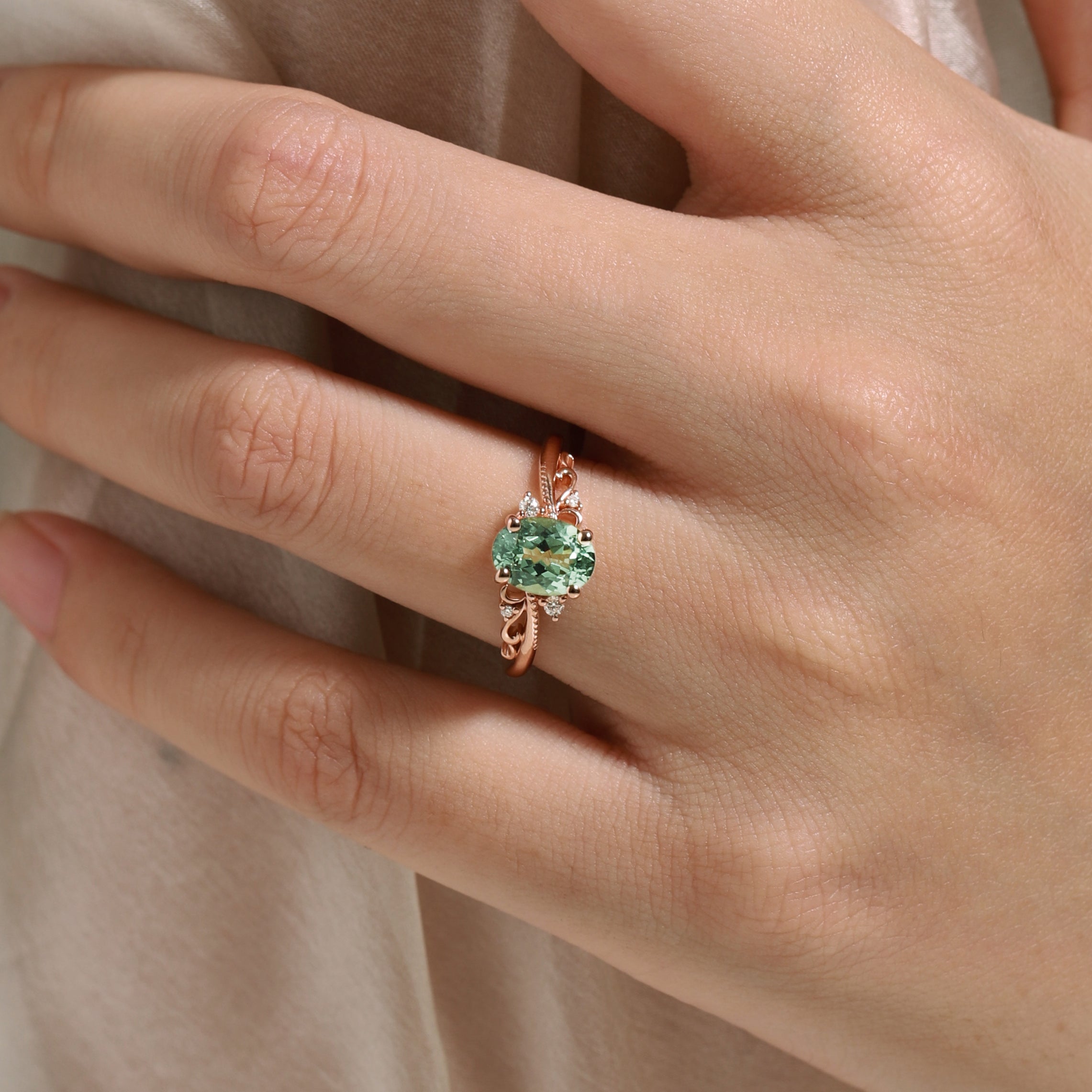 Oval green sapphire engagement ring in rose gold, leaf-inspired design, vintage style.