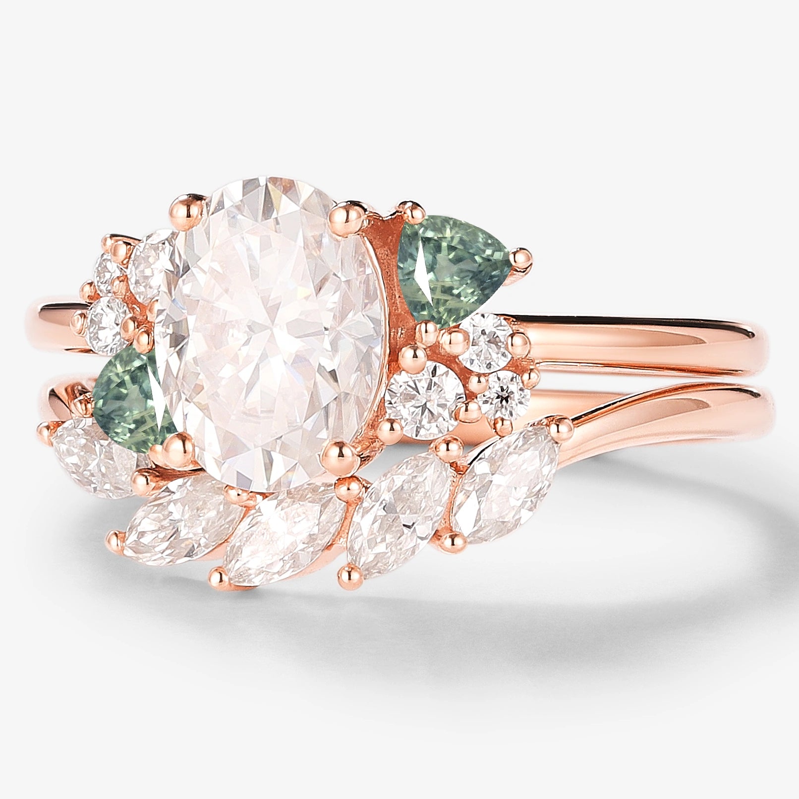 Rose gold bridal set featuring an oval moissanite engagement ring with triangle spinel cluster and wedding band.