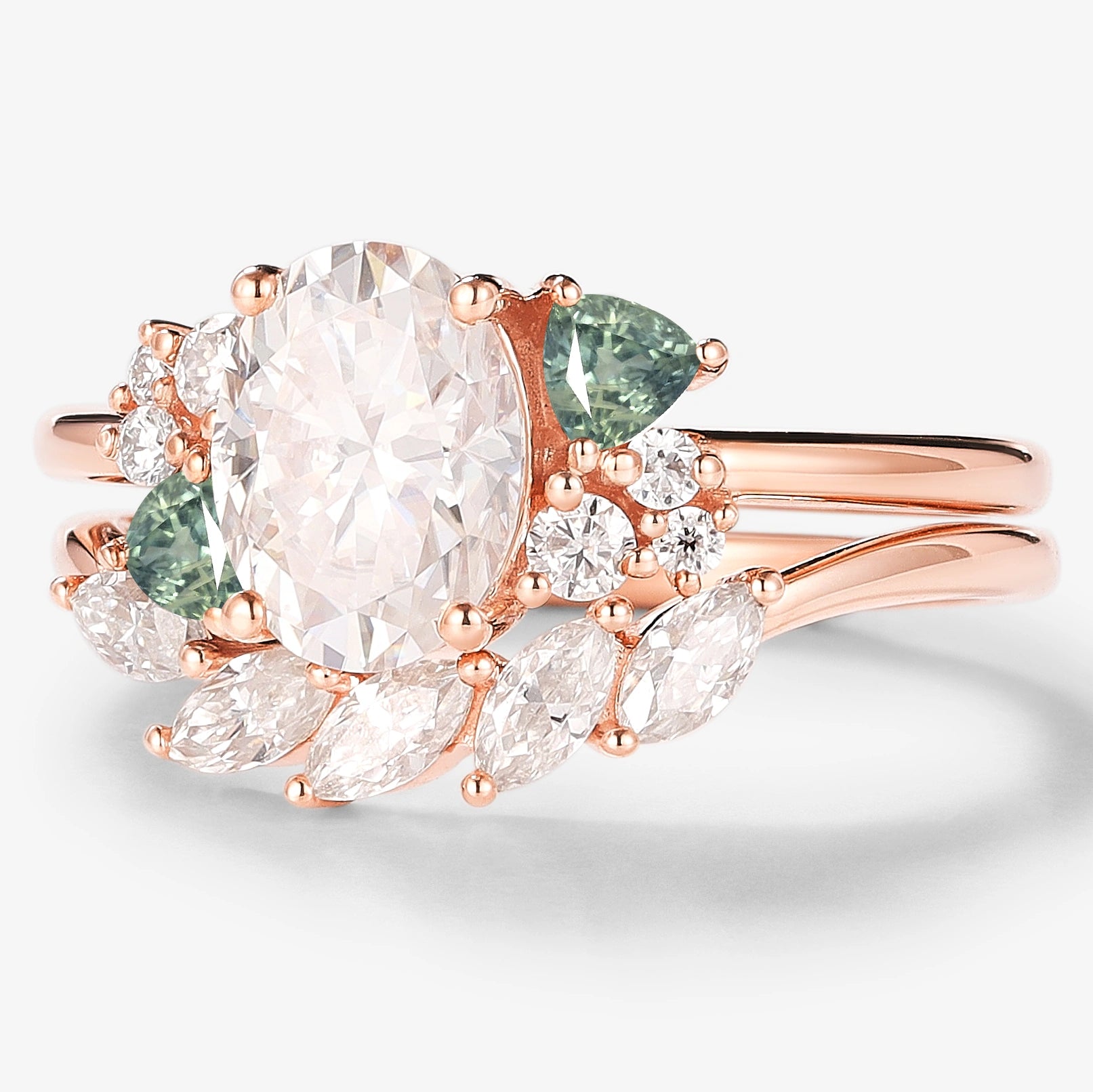 Rose gold bridal set featuring an oval moissanite engagement ring with triangle spinel cluster and wedding band.