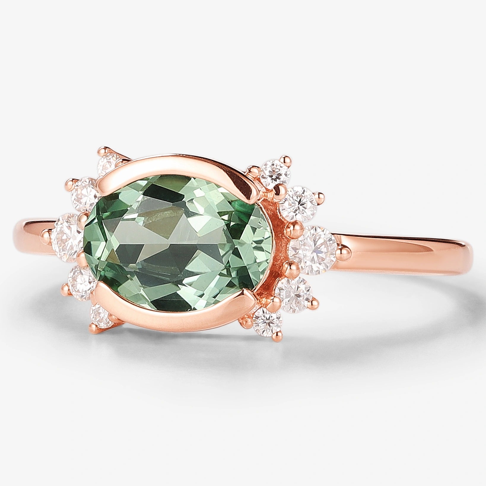 Rose gold engagement ring featuring oval green sapphire center stone with moissanite accents.