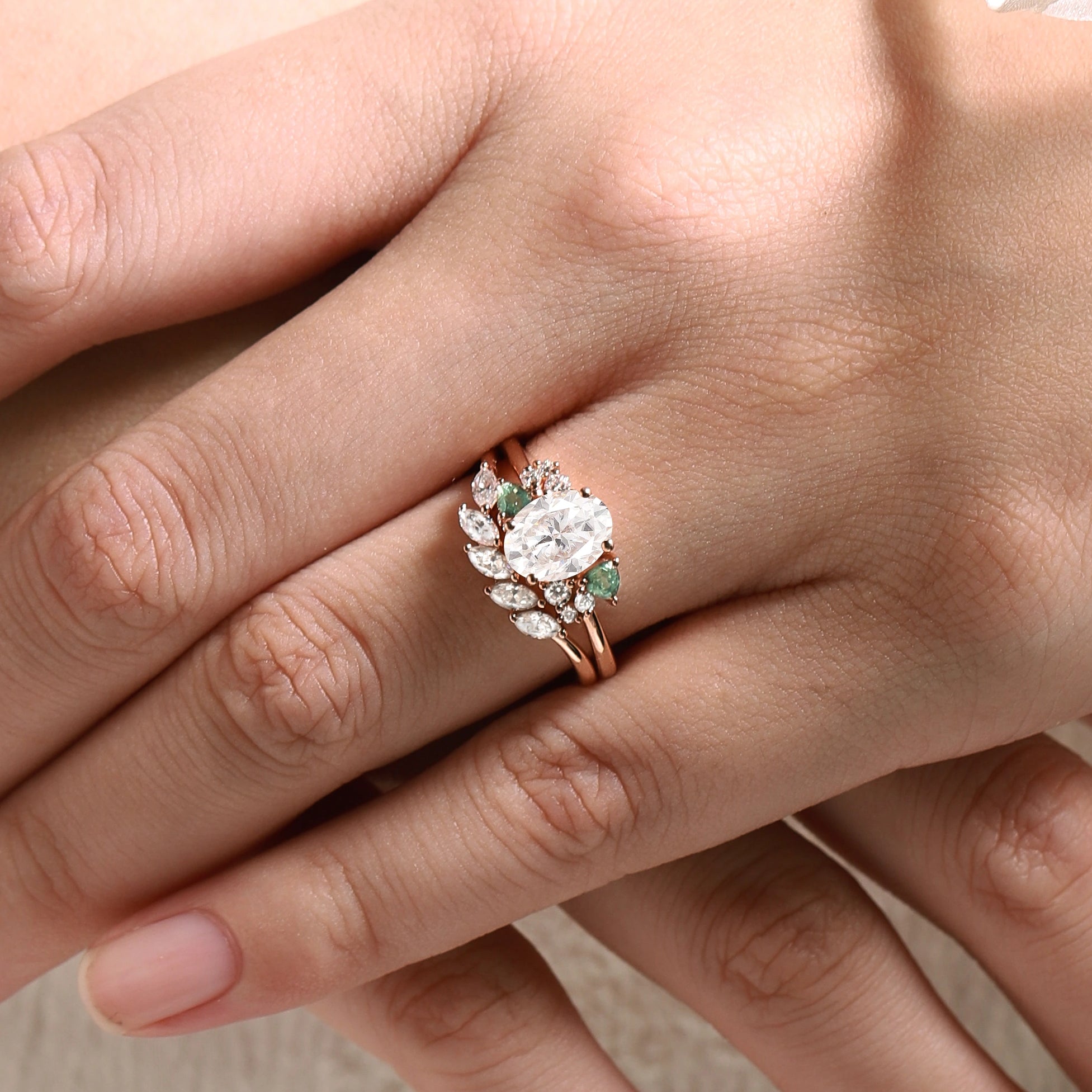 Rose gold oval moissanite engagement ring with triangle spinel accents on a hand. Bridal set ring.