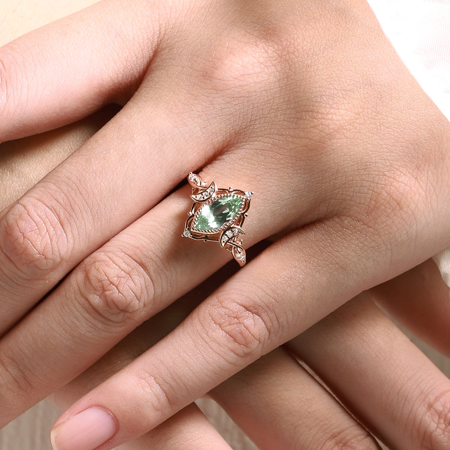 Rose gold marquise green sapphire engagement ring with moon and moissanite accents, on hand, Lahela Jewelry.
