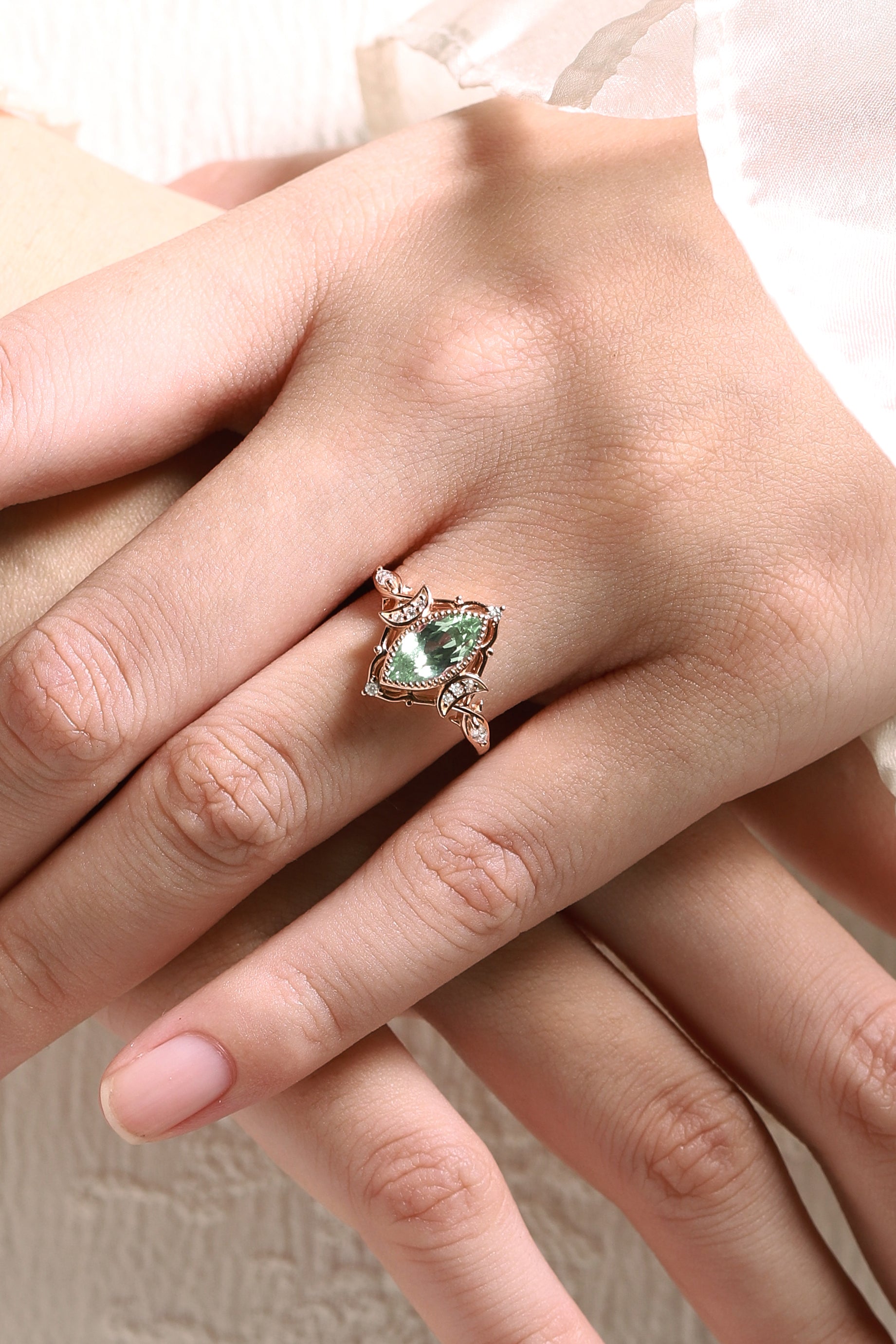 Rose gold marquise green sapphire engagement ring with moon and moissanite accents, on hand, Lahela Jewelry.