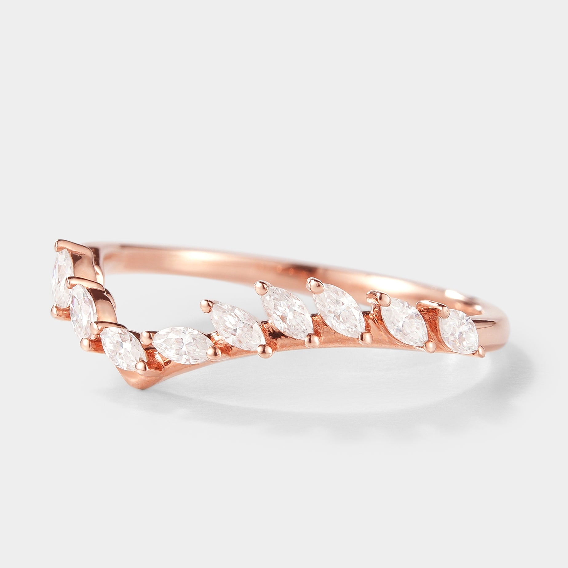 Rose gold curved wedding band with moissanite stones. A unique and modern wedding ring design.