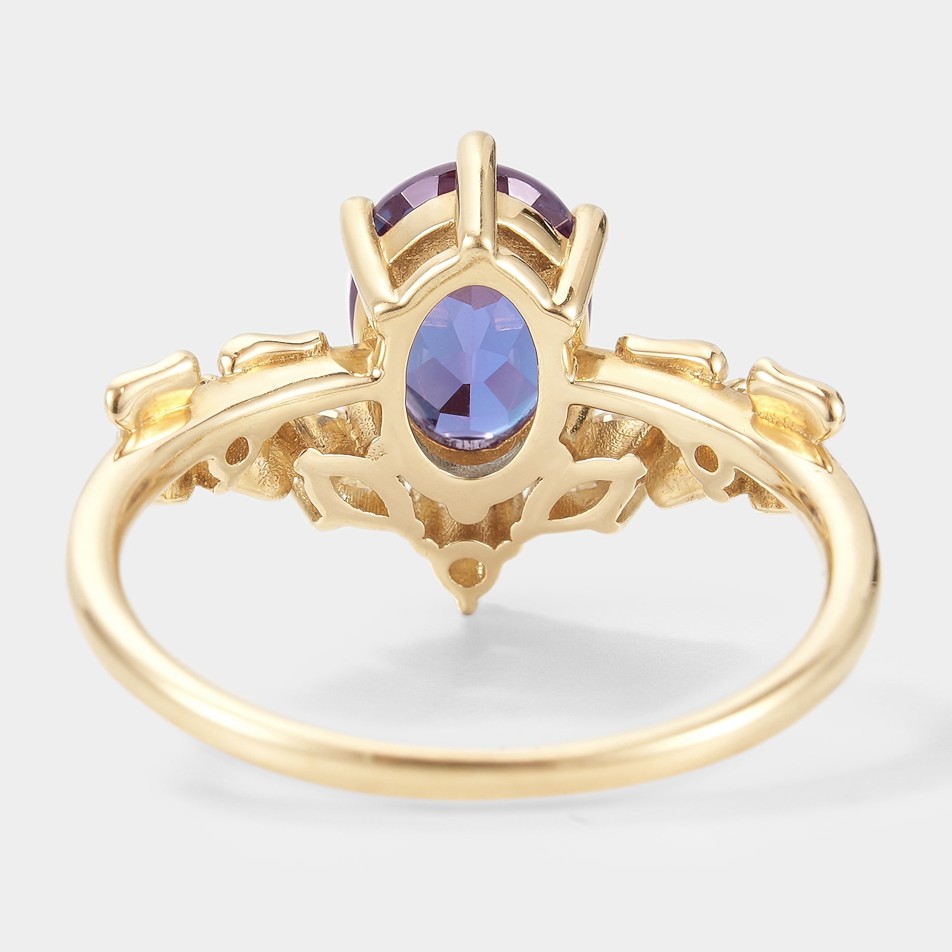 Oval alexandrite engagement ring in yellow gold, with moissanite accents, showing intricate floral design. Wedding ring