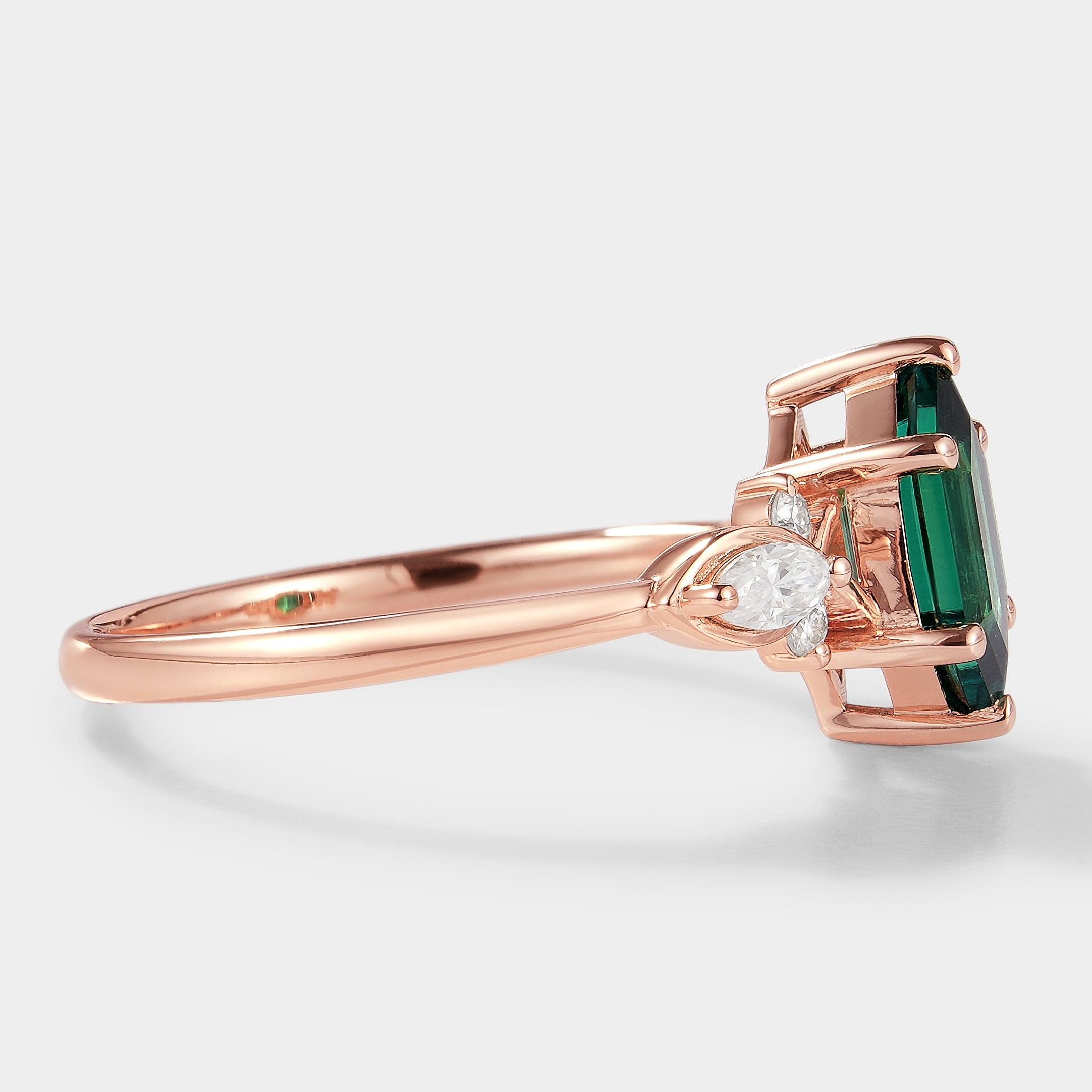 Rose gold engagement ring with a long hexagon-cut lab-grown emerald center stone and moissanite accents, vintage style.