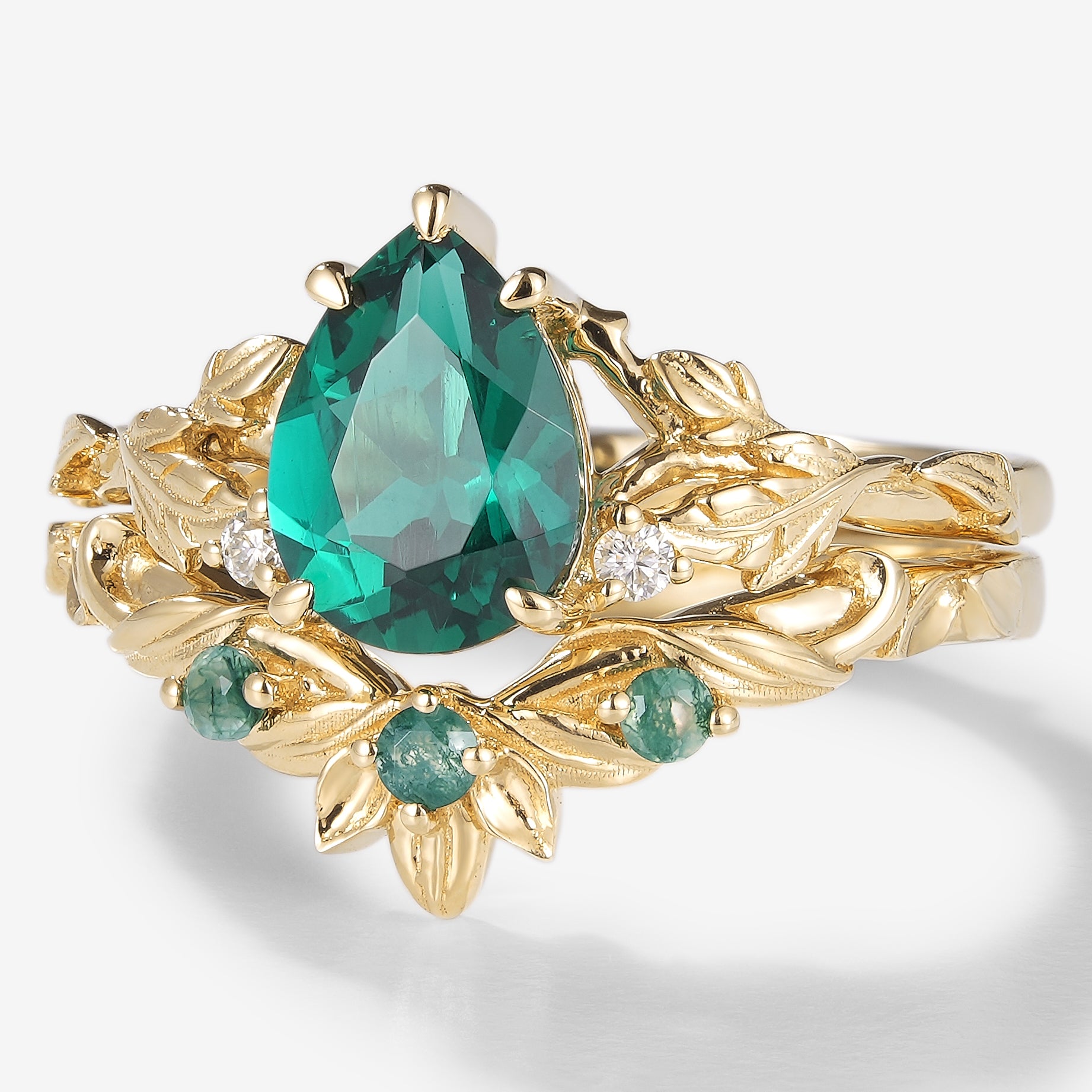 Lab created emerald leaf bridal set in solid gold featuring a pear-cut emerald engagement ring and moss agate wedding band.