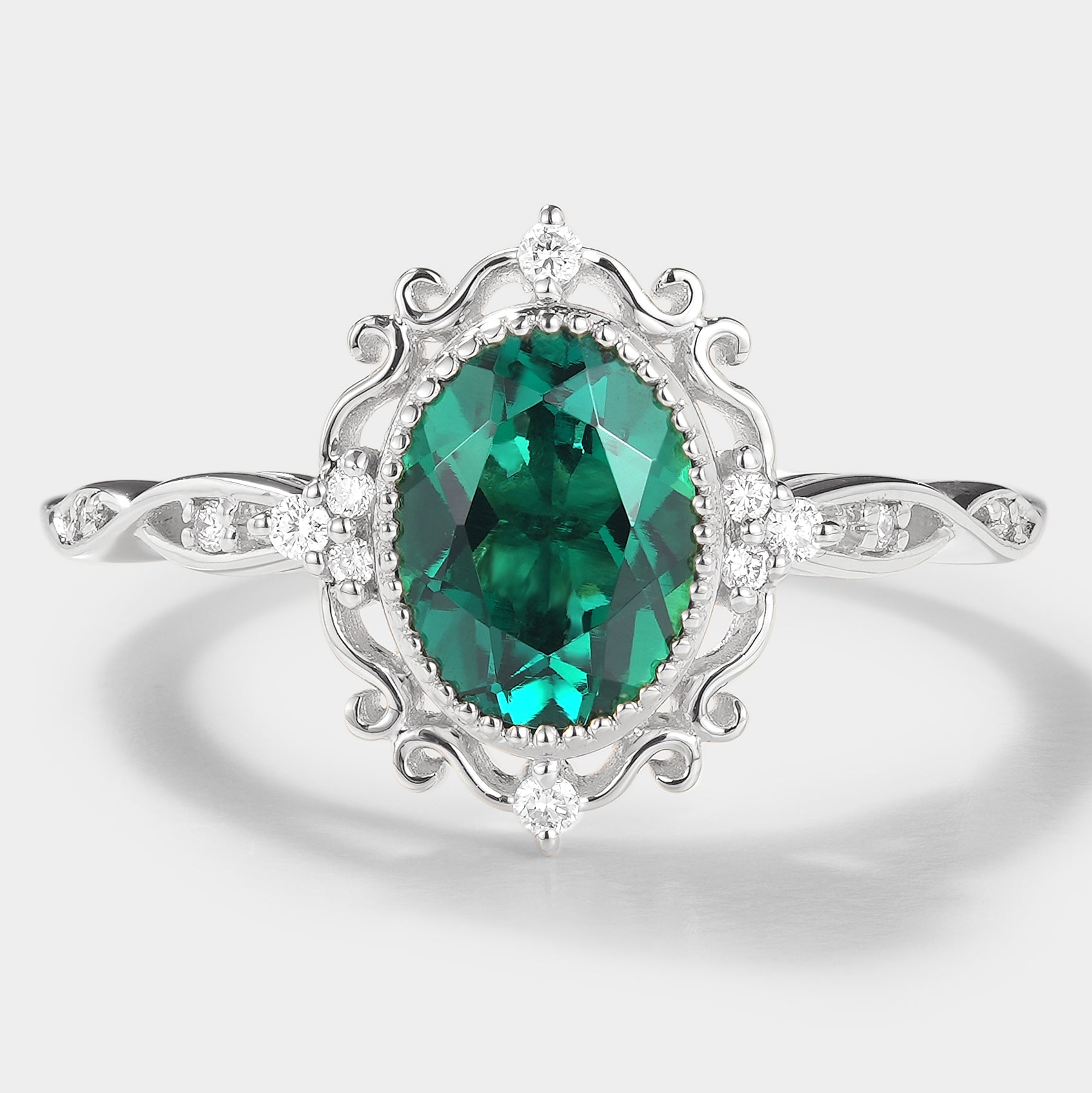 Vintage style lab grown emerald engagement ring, oval cut with moissanite accents, white gold band, royal court design.
