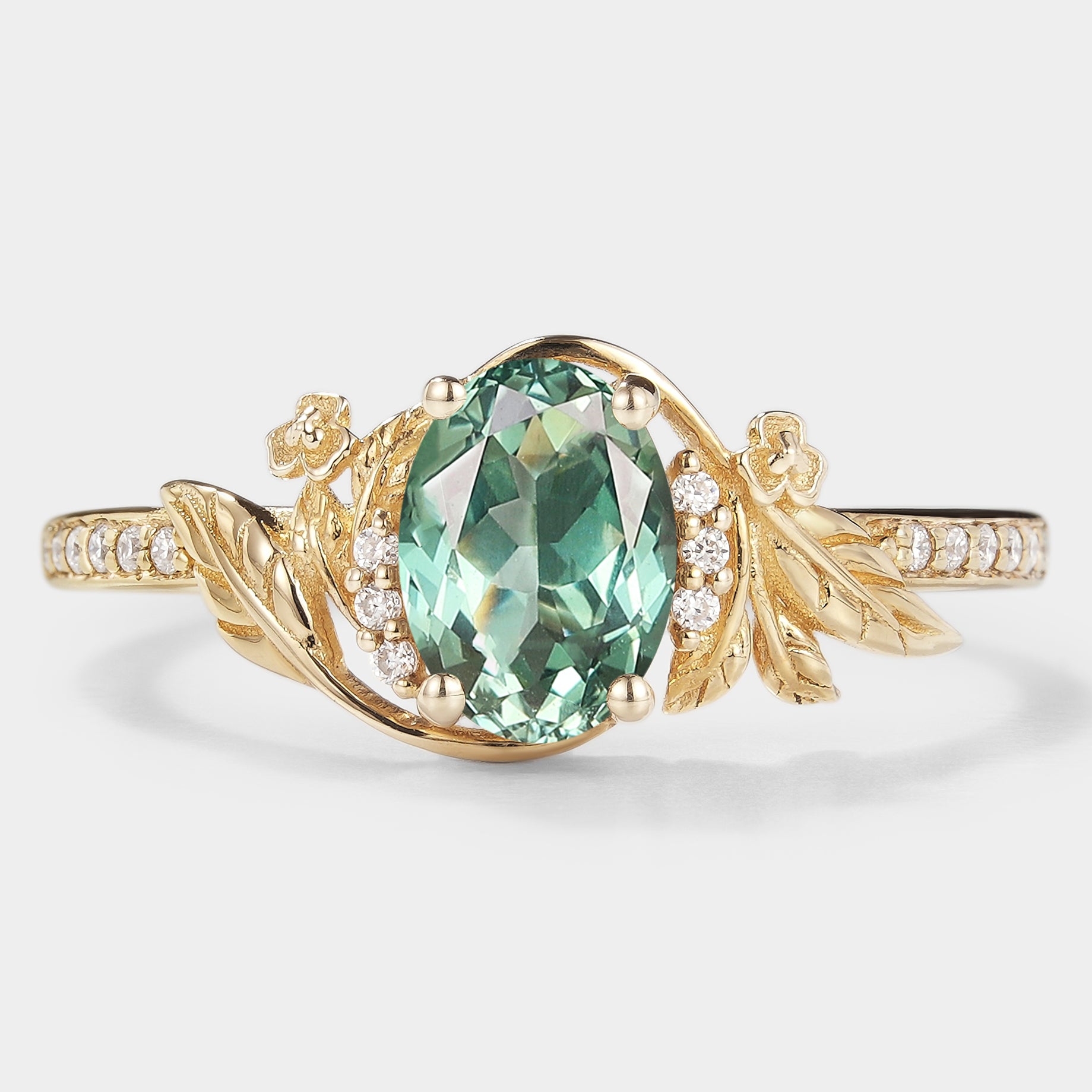 Oval green sapphire engagement ring with leaf and flower accents in gold