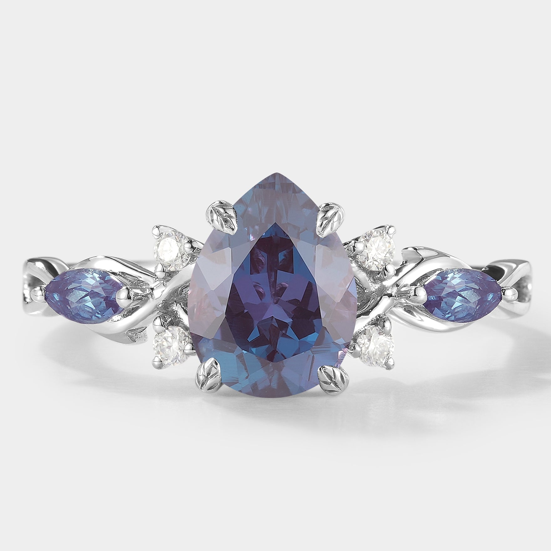 Classic pear-cut alexandrite engagement ring with moissanite accents and leaf design. Lahela Jewelry.