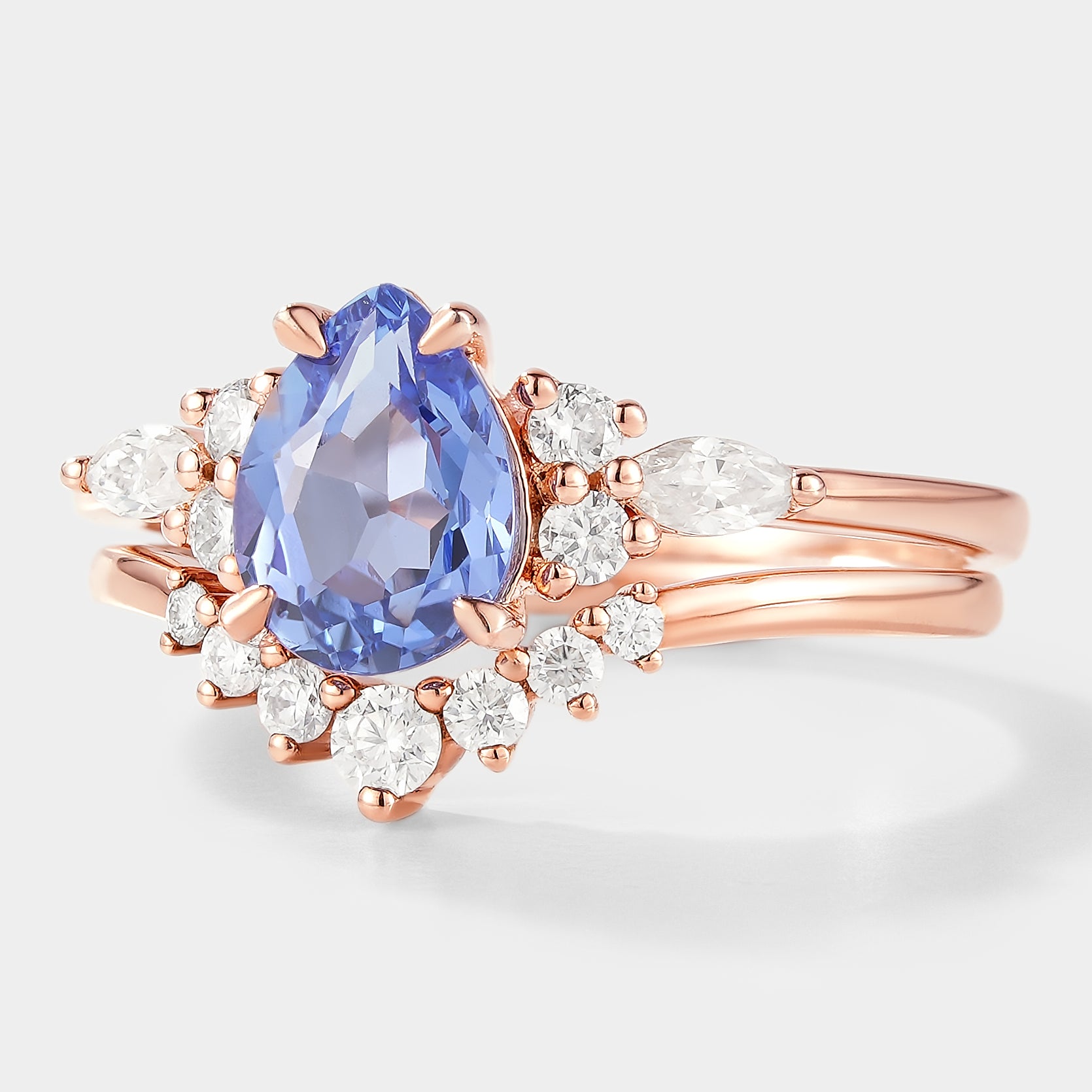 Rose gold pear-cut cornflower sapphire engagement ring with curved moissanite wedding band. Bridal set.