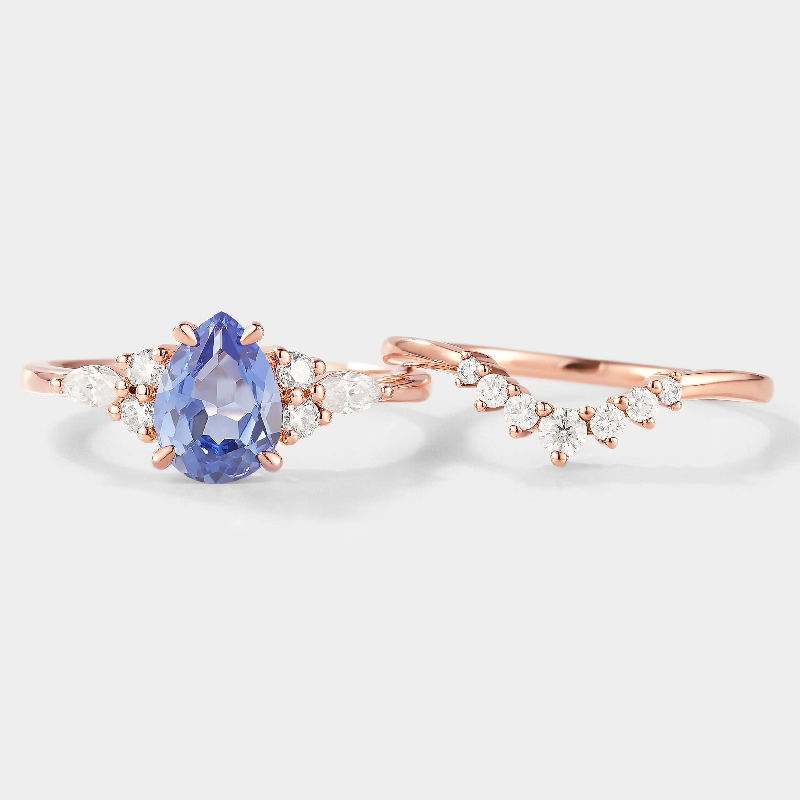 Rose gold pear cut cornflower sapphire engagement ring with moissanite accents and curved wedding band. Bridal set.