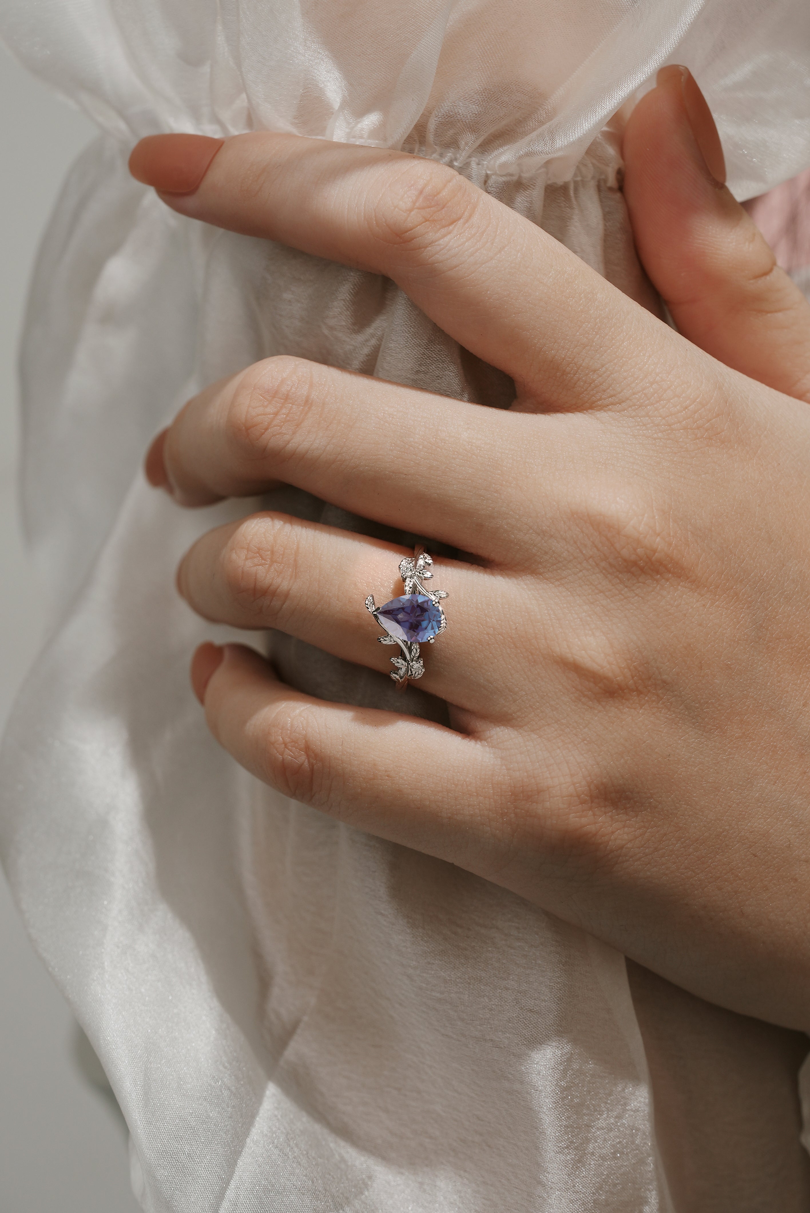 Pear cut alexandrite leaf engagement ring. White gold, moissanite accents. Perfect for proposals, vintage style.