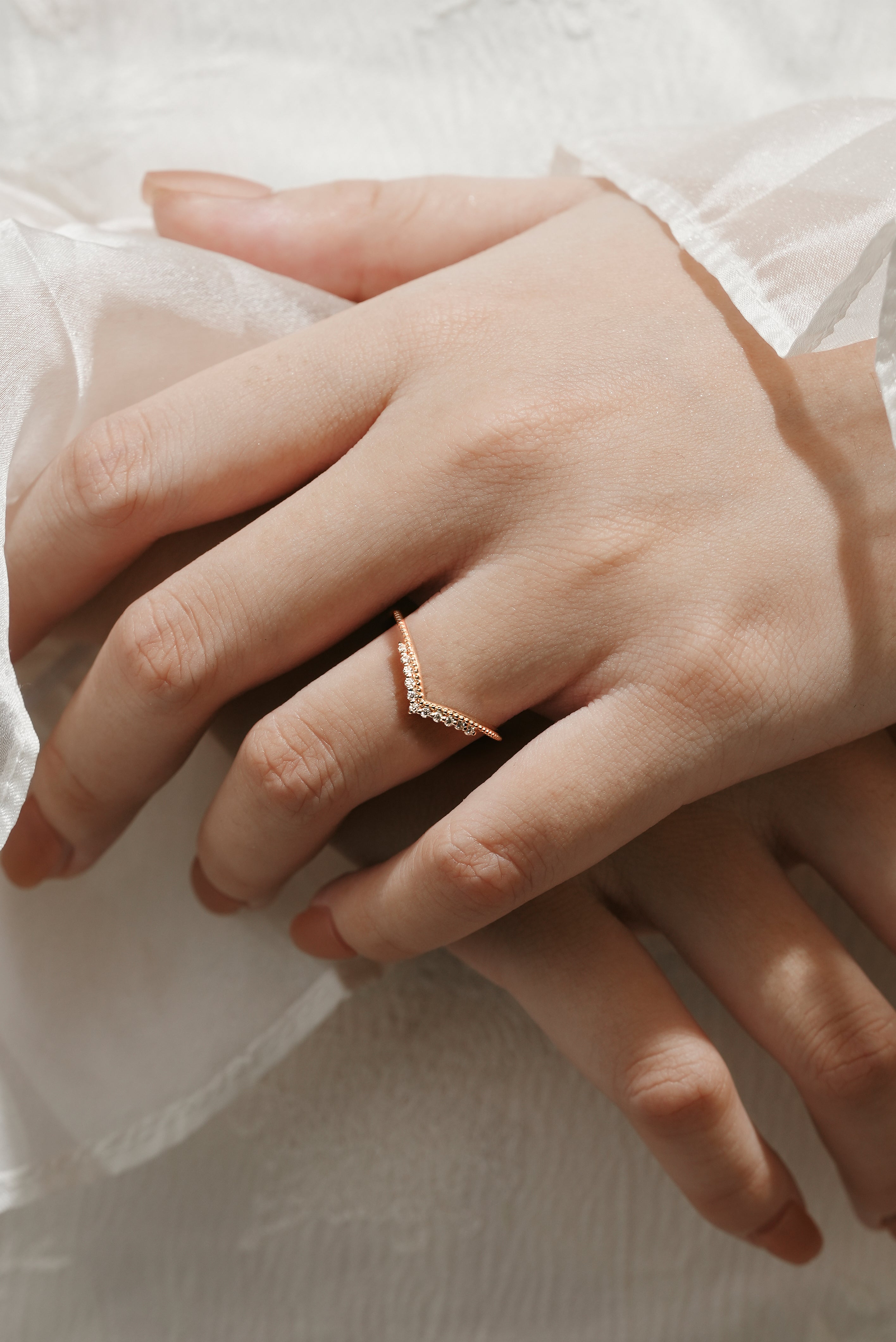 Rose gold moissanite V-shaped wedding band on a hand, delicate bridal set.