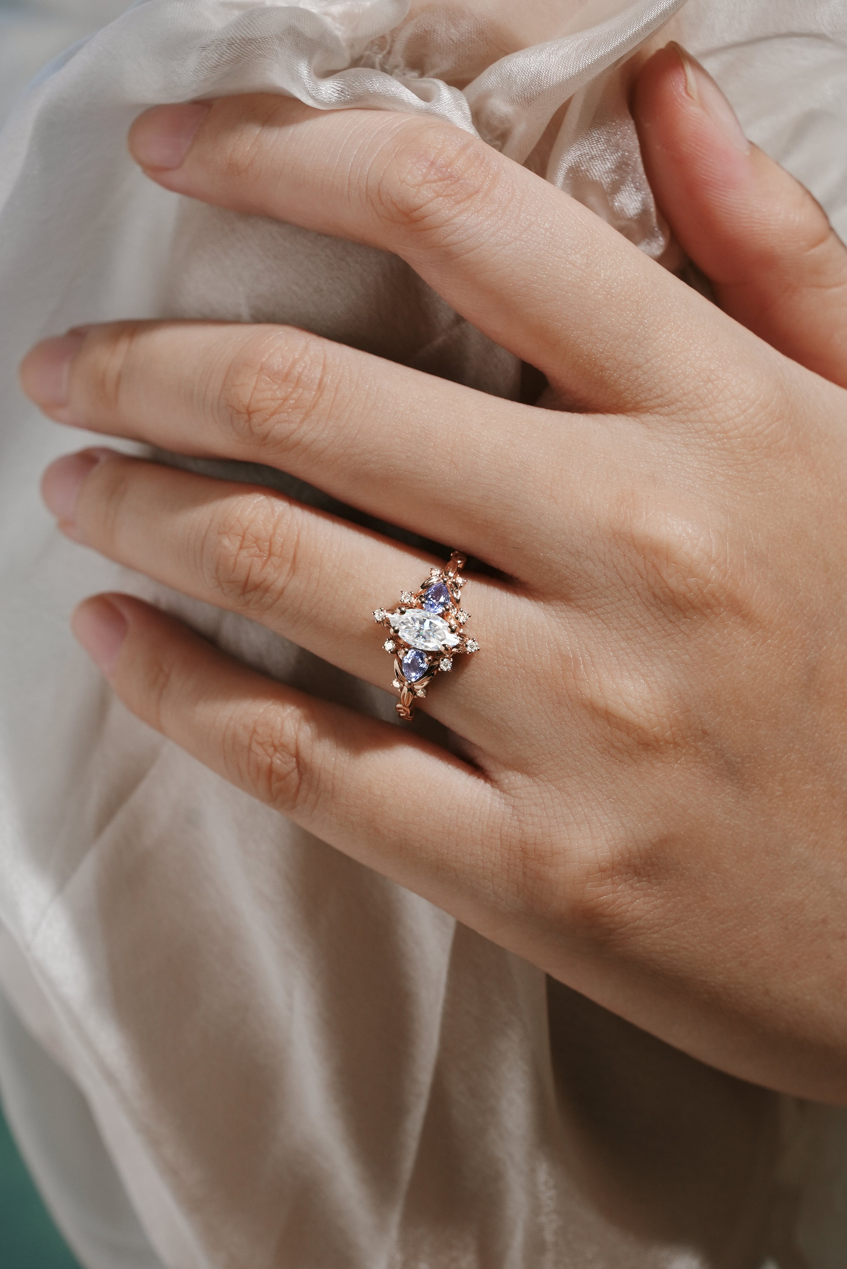 Hand wearing Marquise Cut Moissanite Leaf Engagement Ring with Sapphire Cluster