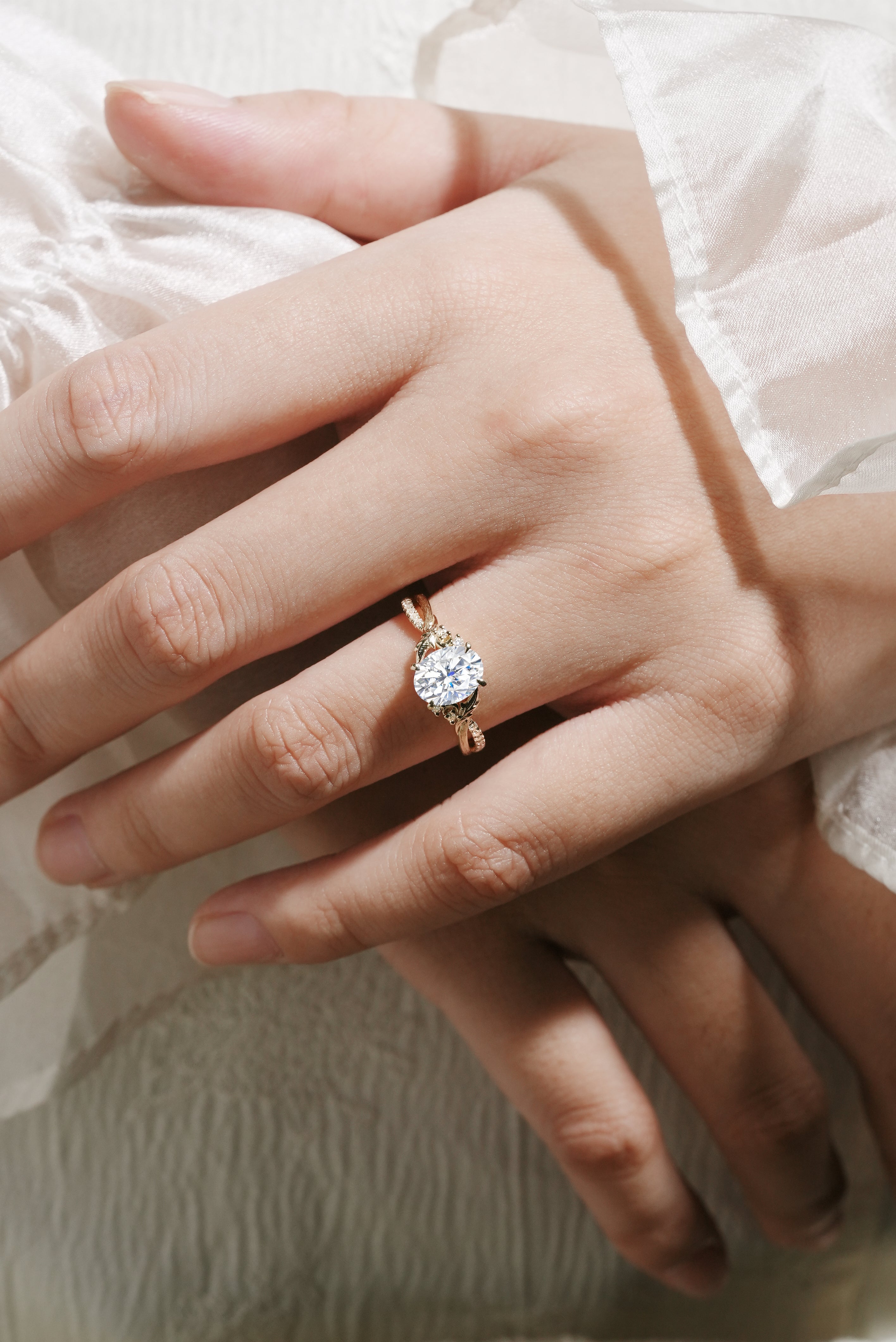 Oval moissanite engagement ring in yellow gold. Features leaf and bark band, bridal jewelry. Handmade detail.