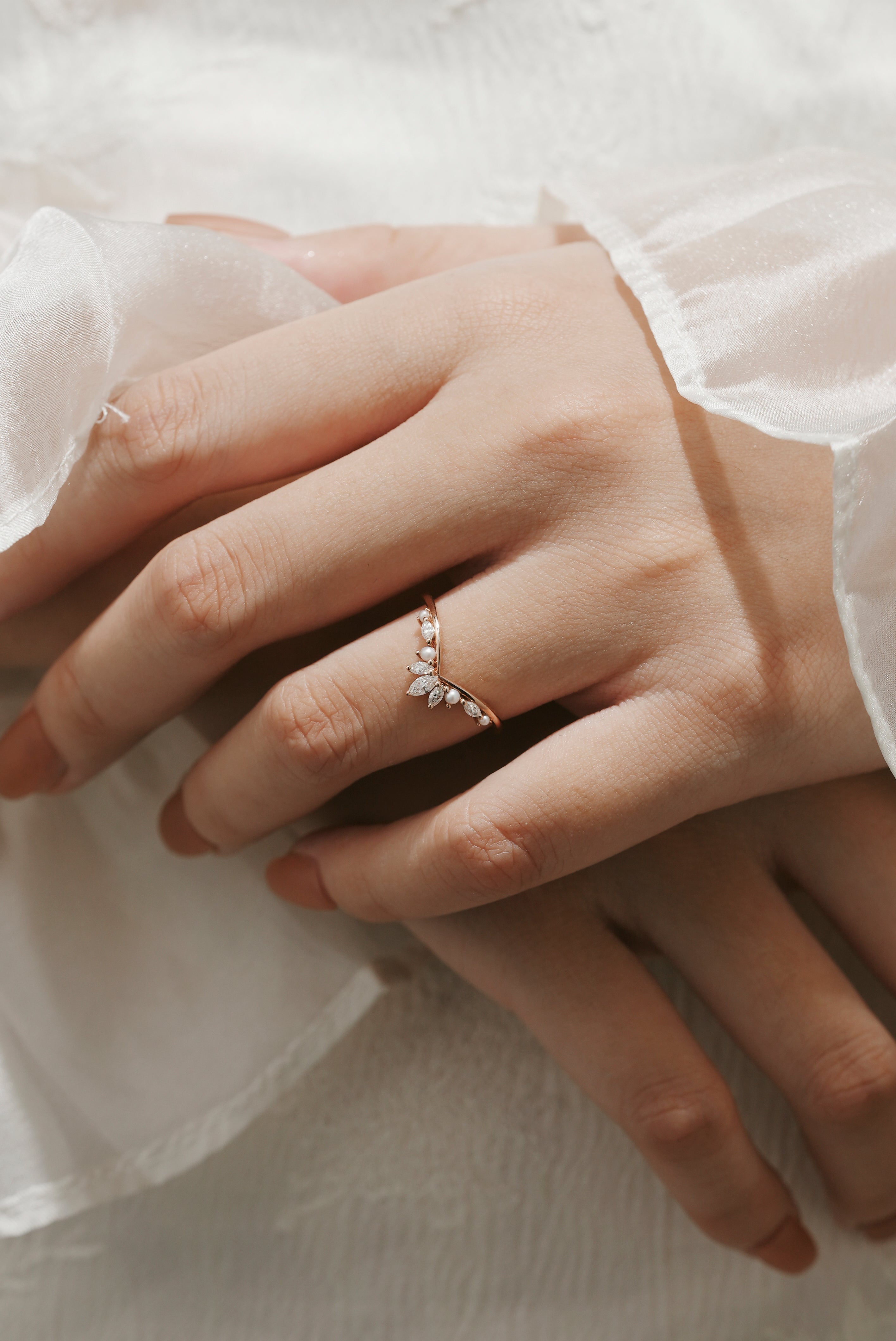 Rose gold curved moissanite and pearl wedding band on a hand