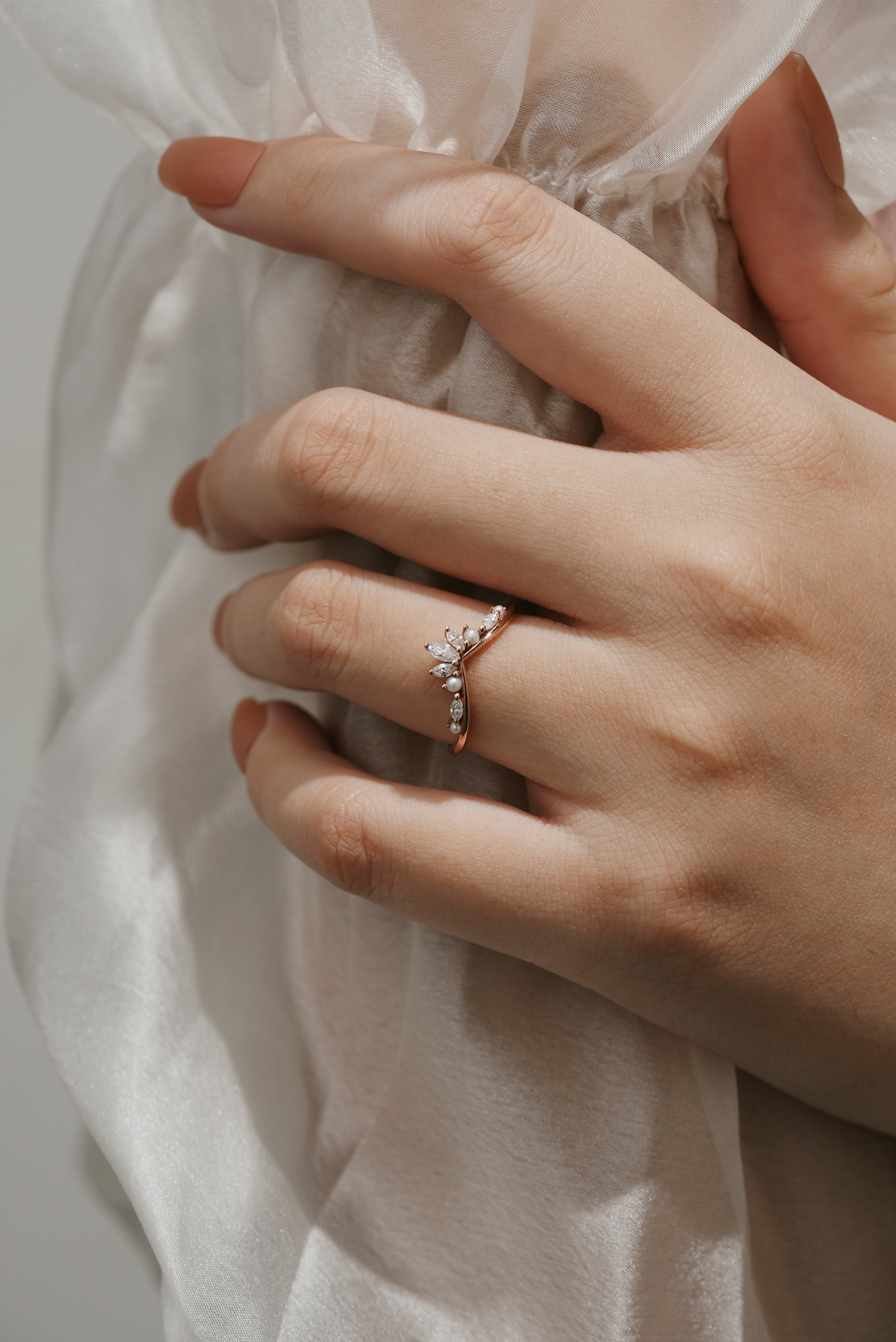 Rose gold curved moissanite and pearl wedding band on a hand