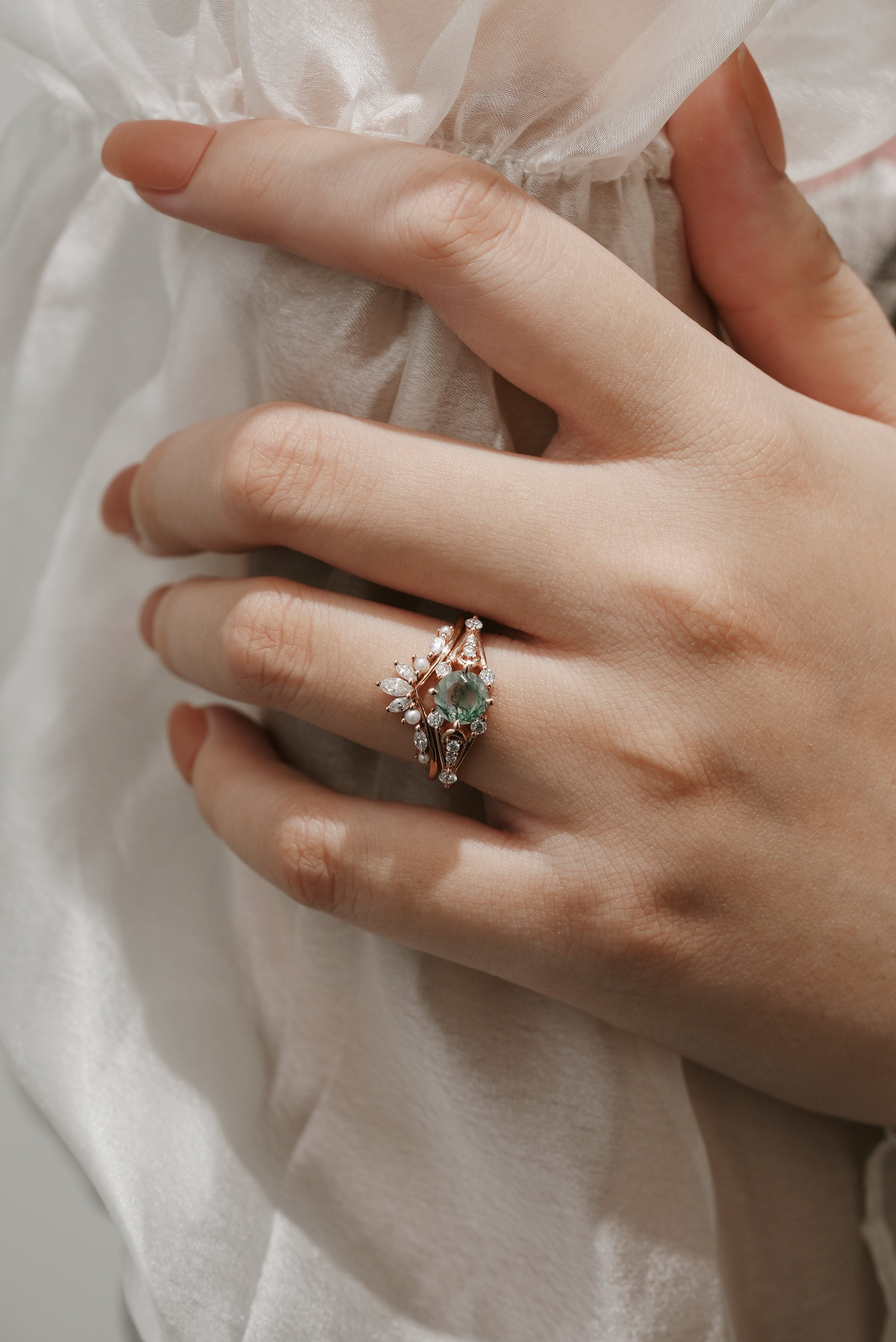 Woman's hand wearing Moss Agate moon engagement ring and wedding band set