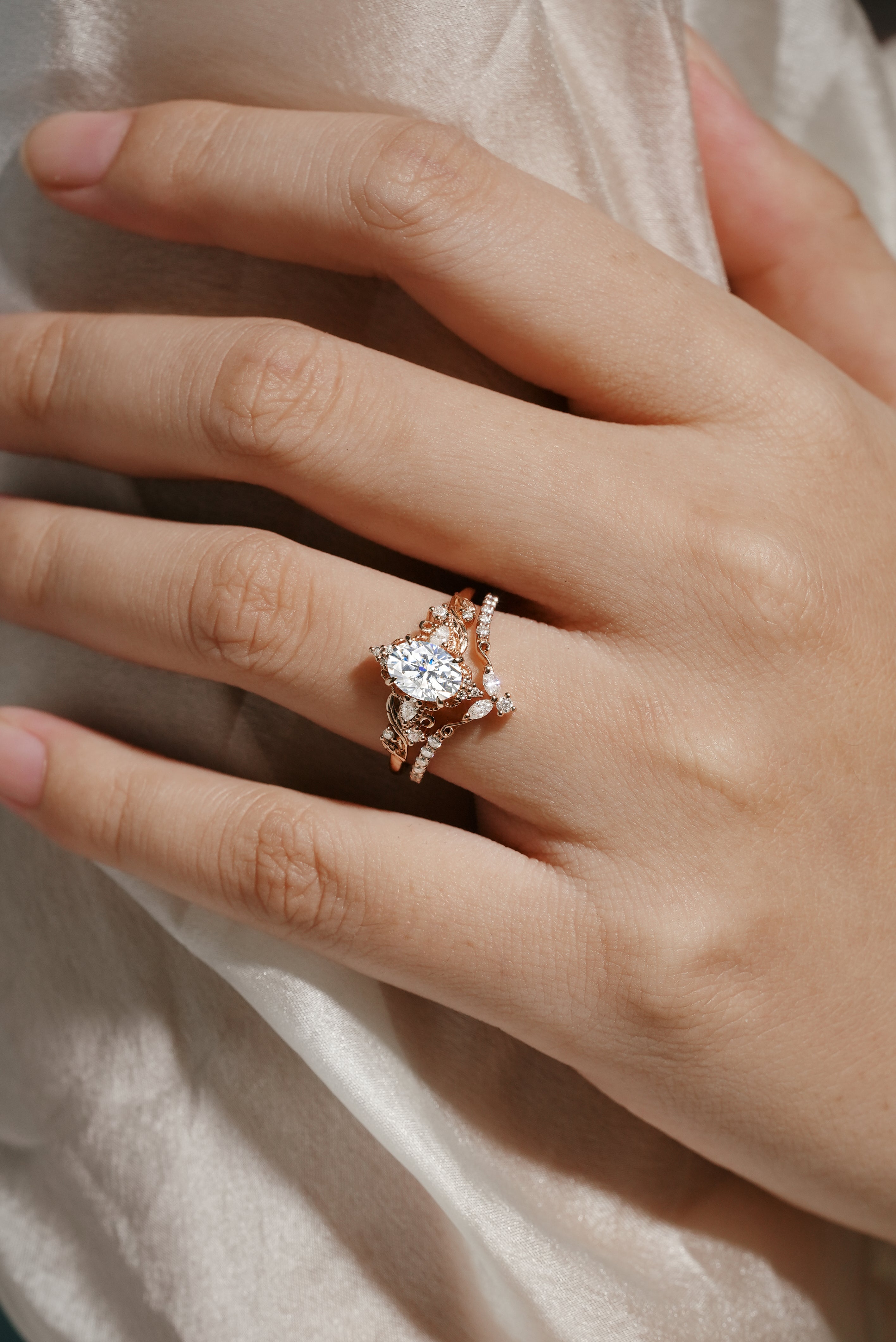 Rose gold leaf-inspired moissanite ring set on hand, bridal jewelry. Includes engagement ring and wedding band.