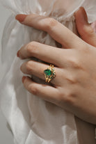 Woman's hand wearing a gold pear-cut emerald leaf bridal set; wedding and engagement ring