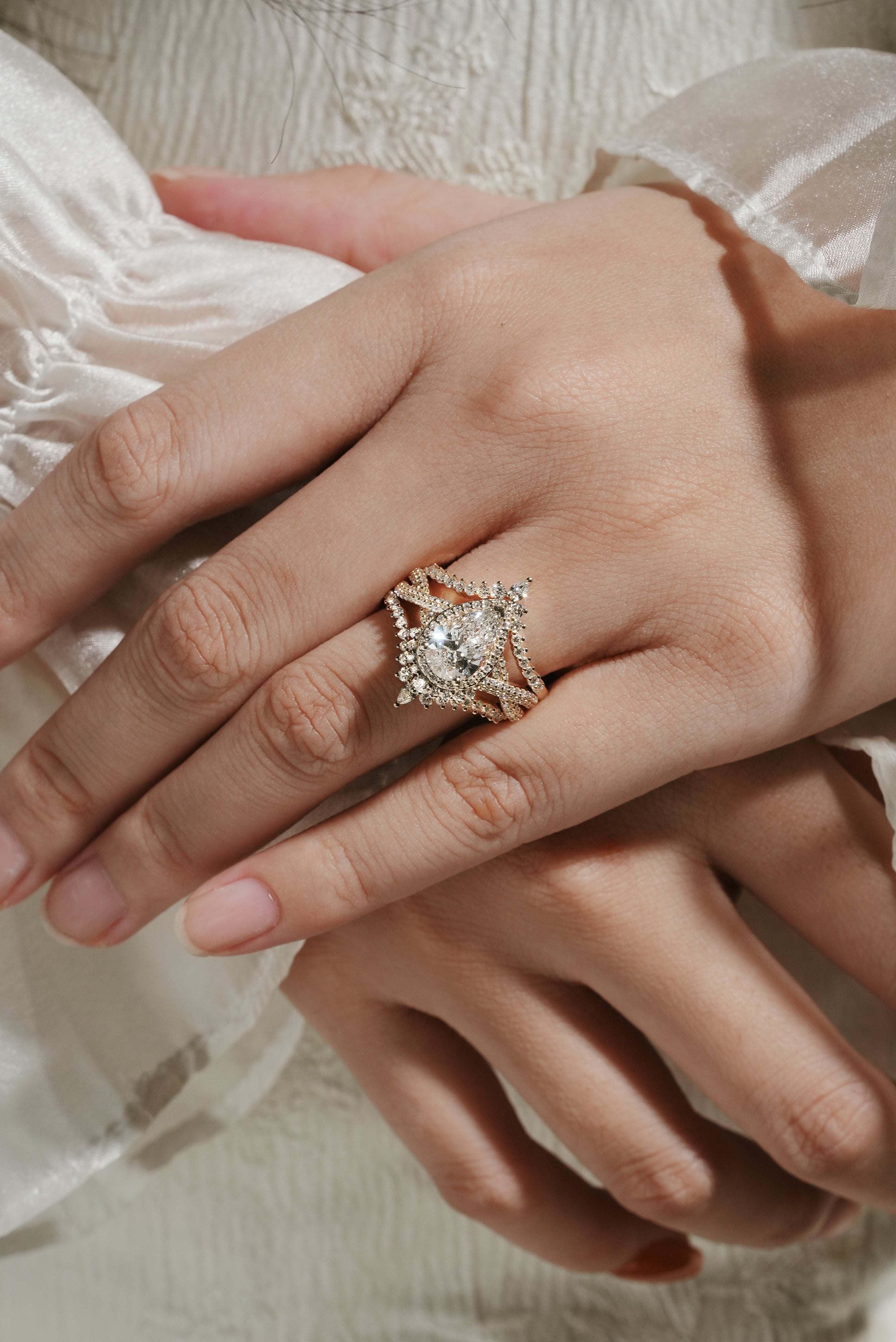 Woman's hand wearing a pear cut halo moissanite engagement ring set