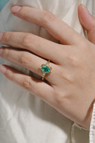 Vintage emerald engagement ring with lab-grown emerald and moissanite accents, gold band.