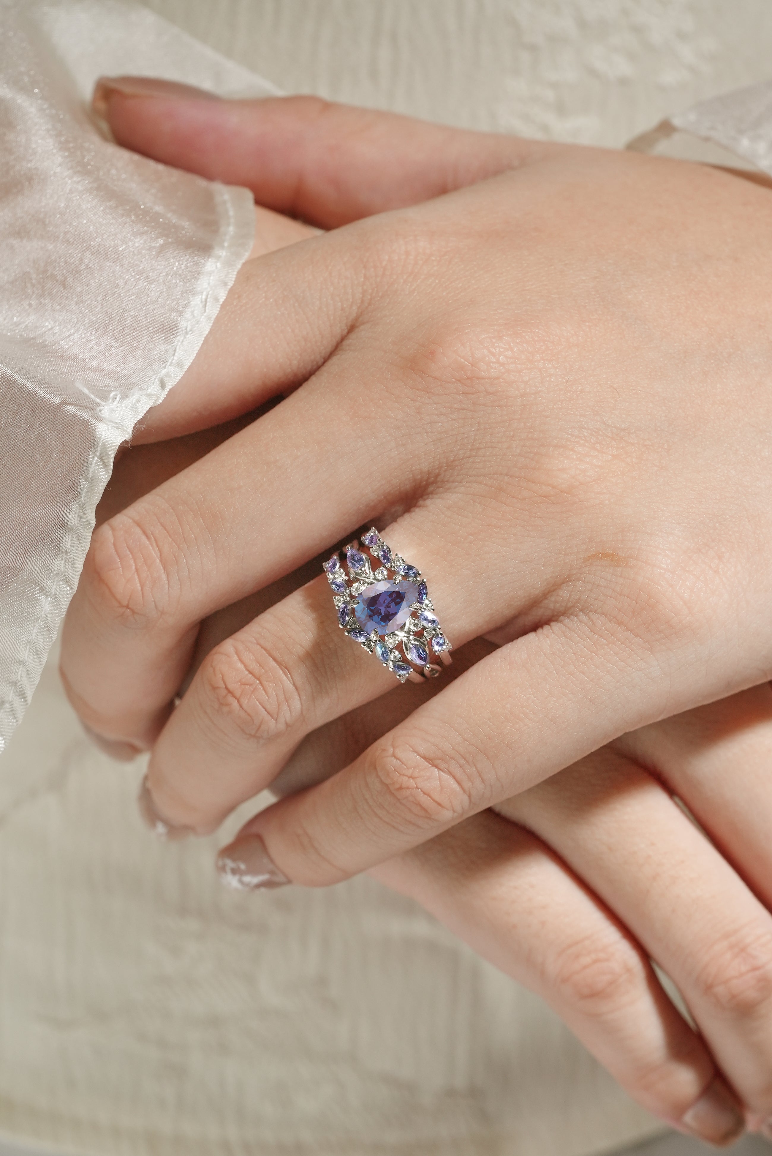 Alexandrite pear cut engagement ring with enhancer wedding band on finger