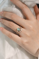 Hand wearing a green sapphire engagement ring and wedding band set