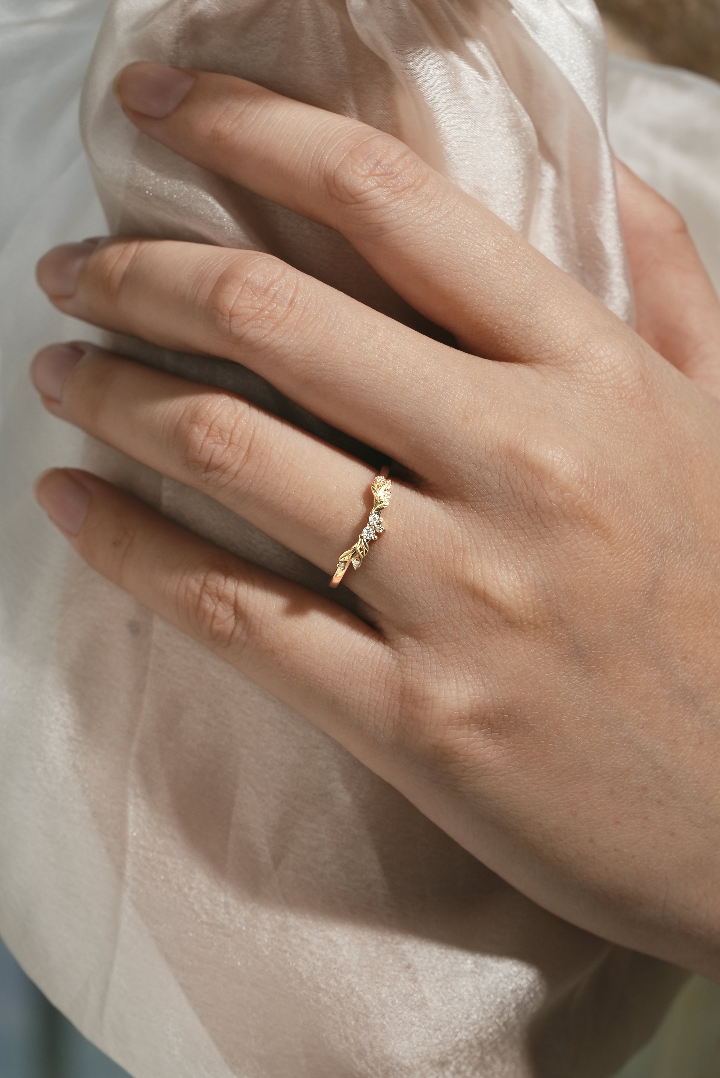 Gold wedding band with leaf pattern and moissanite stones, nature-inspired design.