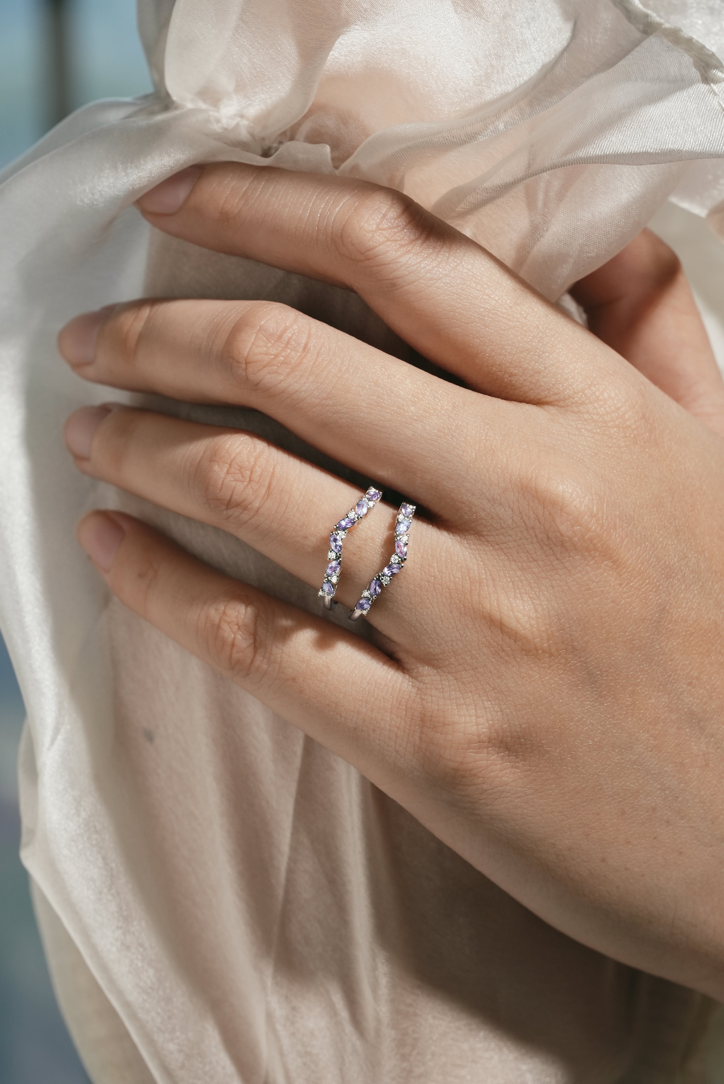 Close-up of an Alexandrite enhancer wedding band on a hand, showcasing moissanite stones, bridal set ring.