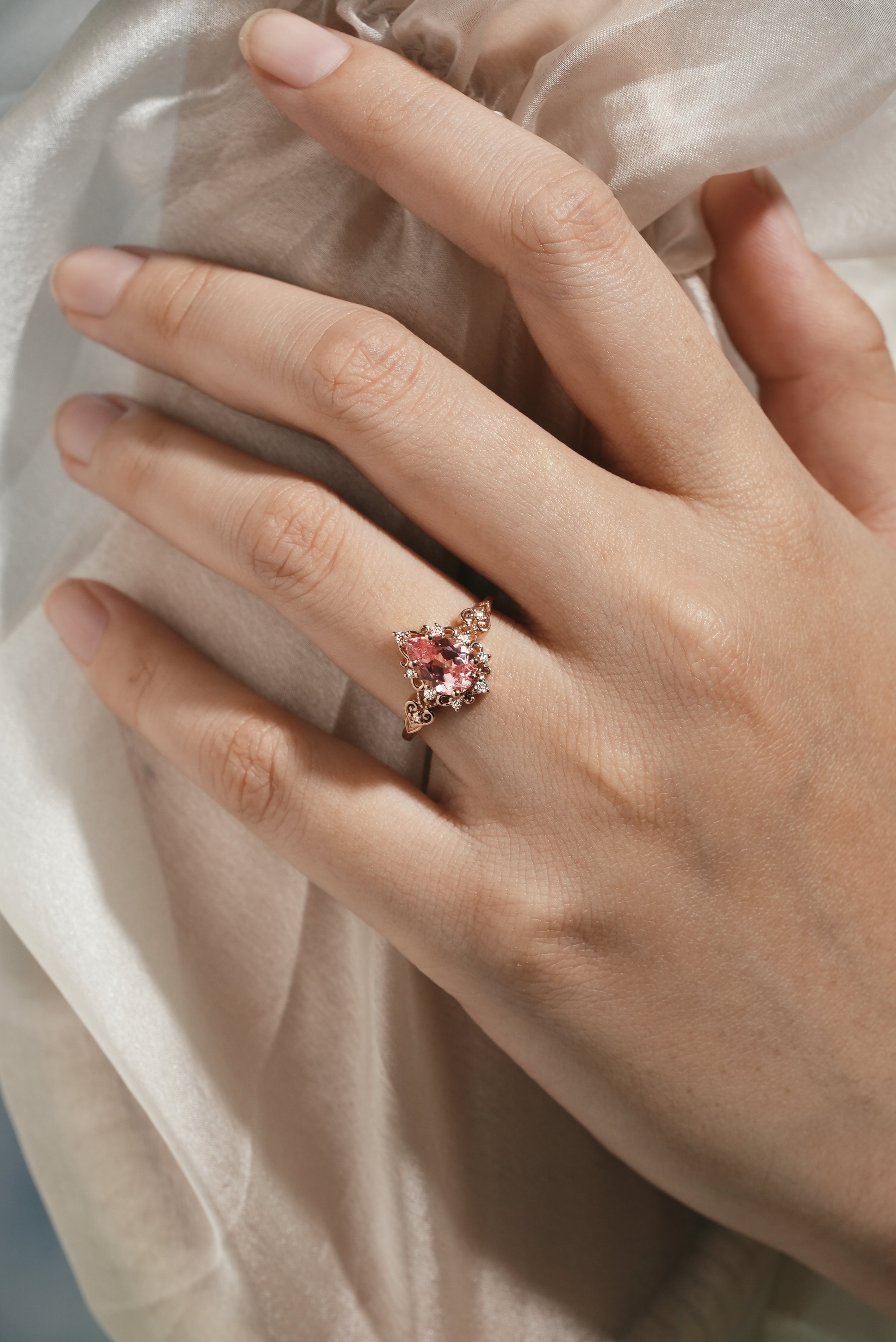 Vintage Padparadscha sapphire engagement ring on a hand, rose gold
