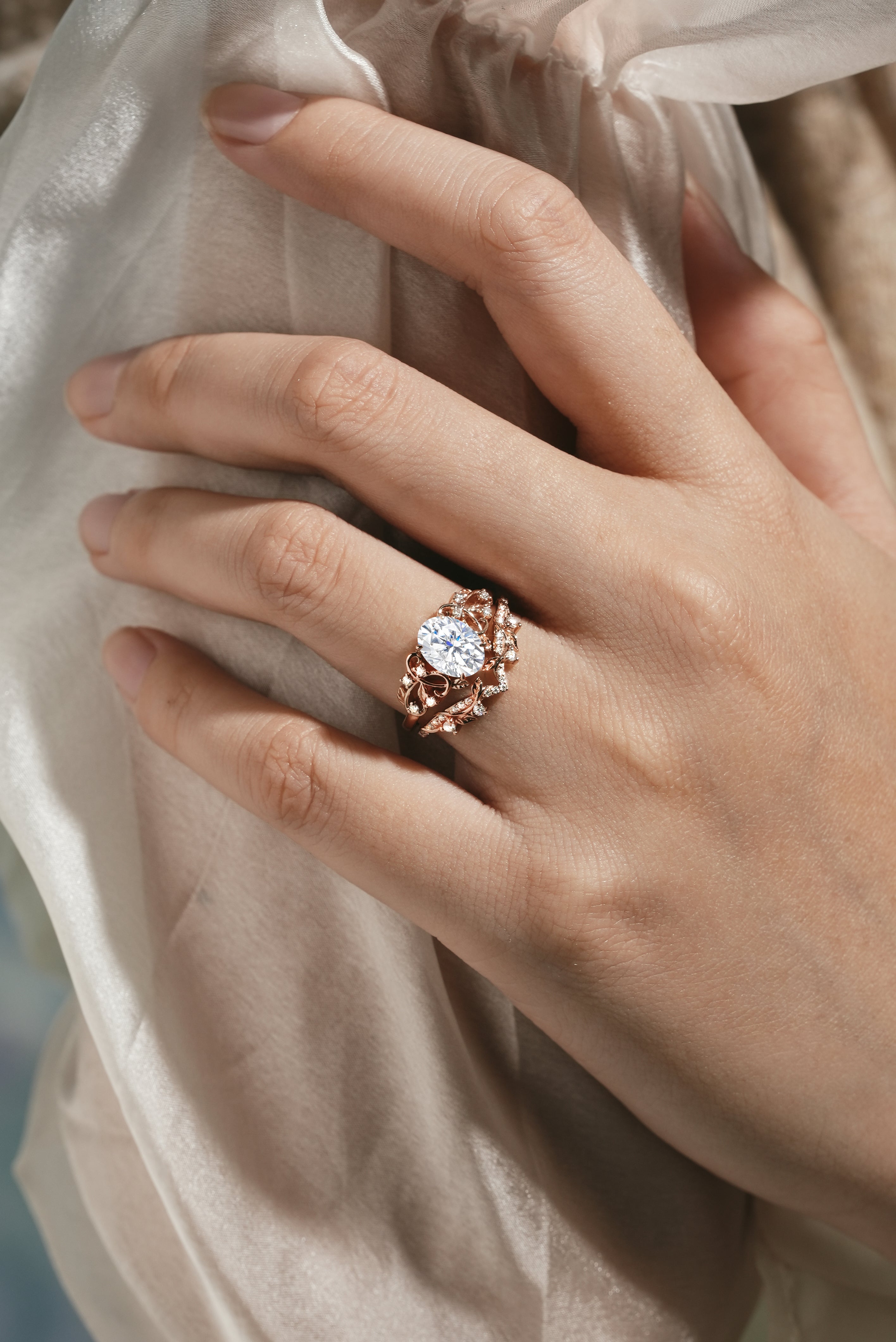 Rose gold leaf engagement ring set with oval moissanite on a hand