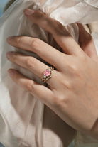 Heart-cut Padparadscha engagement ring set on a hand