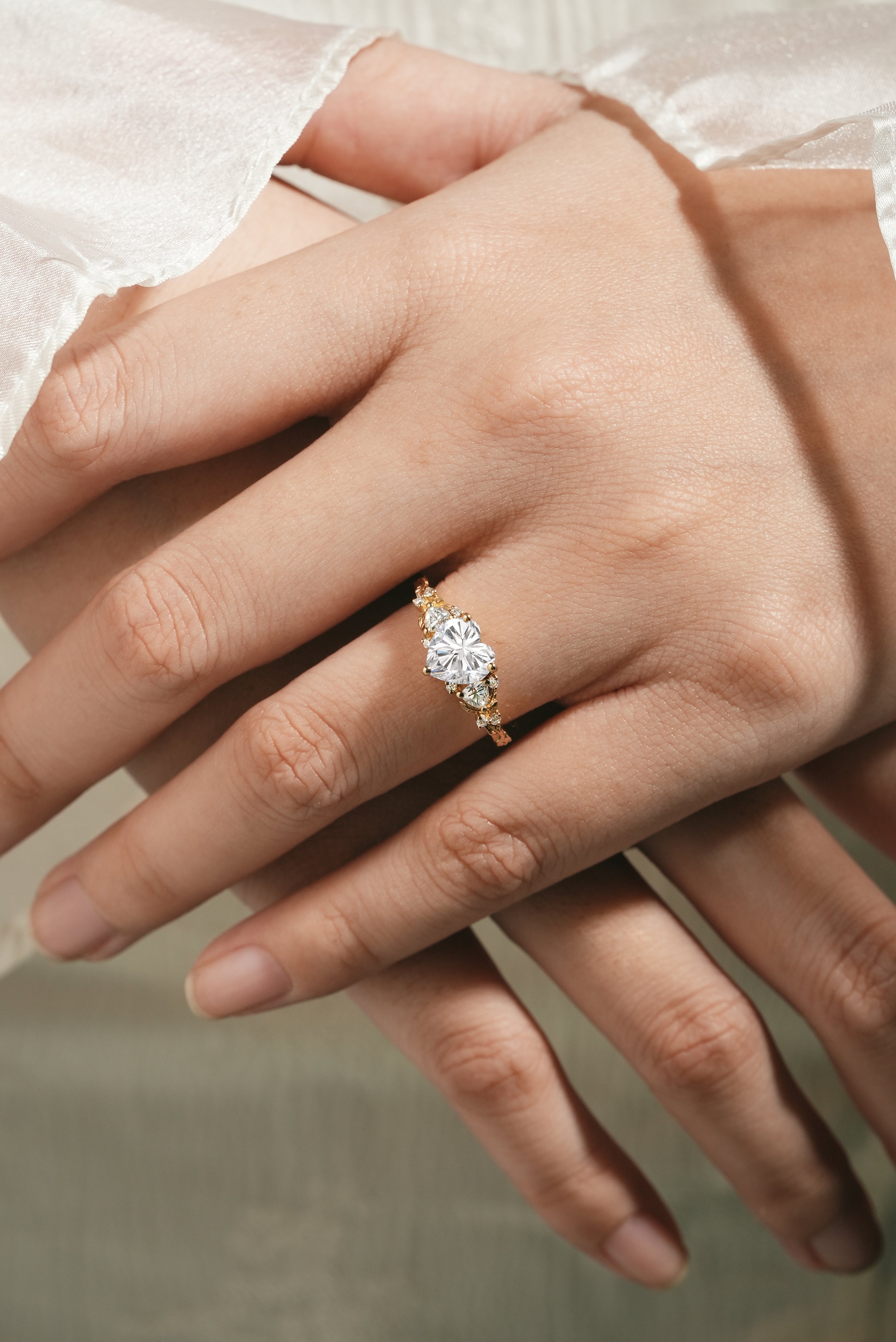 Elegant heart-cut moissanite ring with leaf accents on a woman's hand.