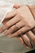 Heart-cut Padparadscha engagement ring on a hand, gold band.