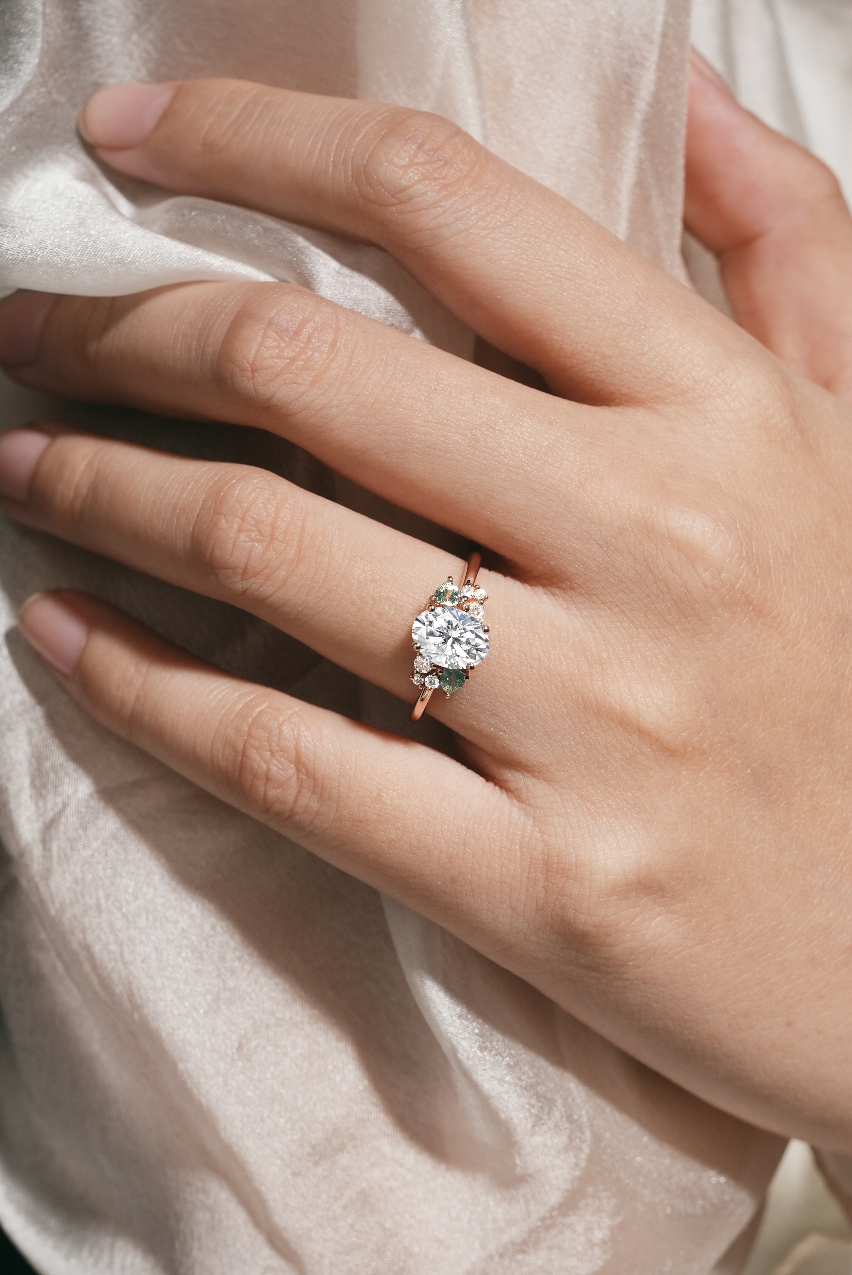 Rose gold oval moissanite ring with spinel cluster on hand