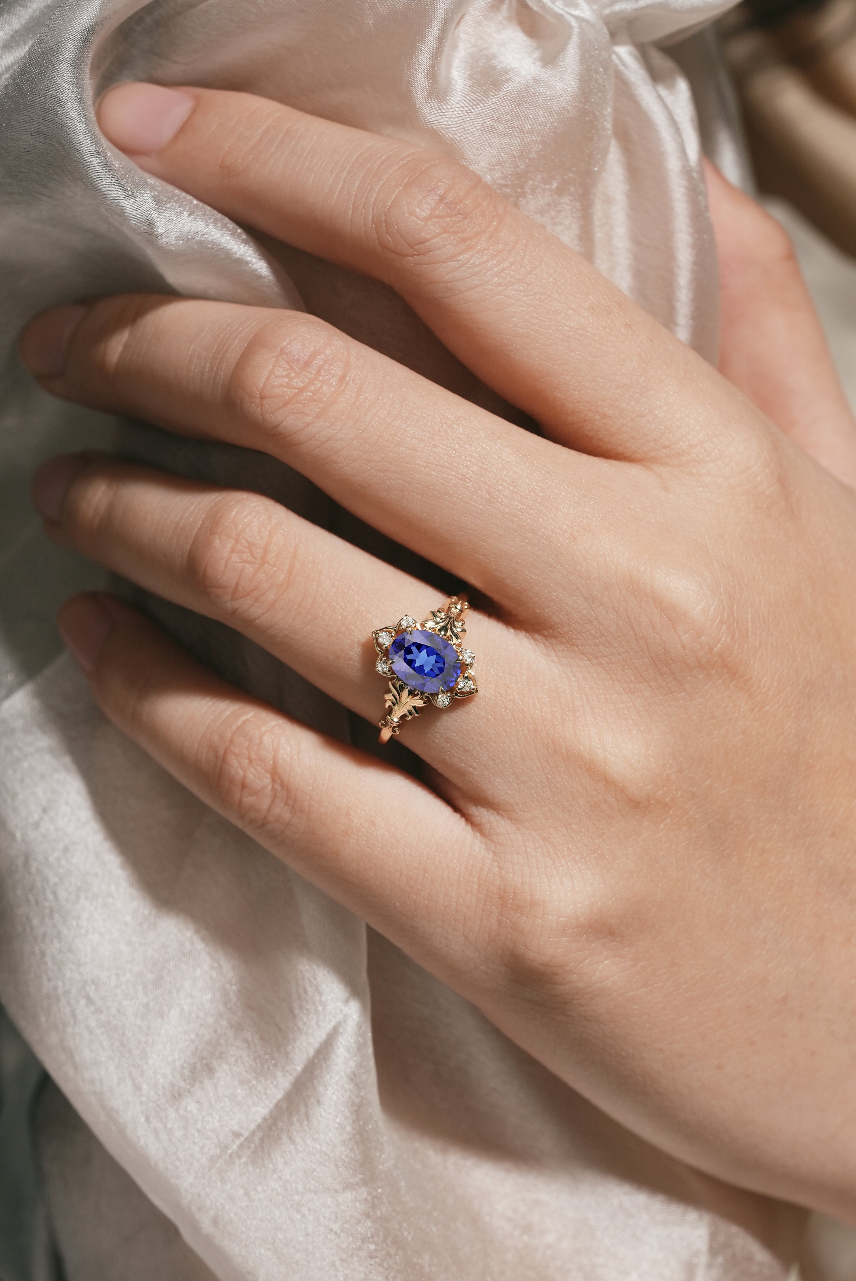 Woman's hand wearing oval royal blue sapphire engagement ring