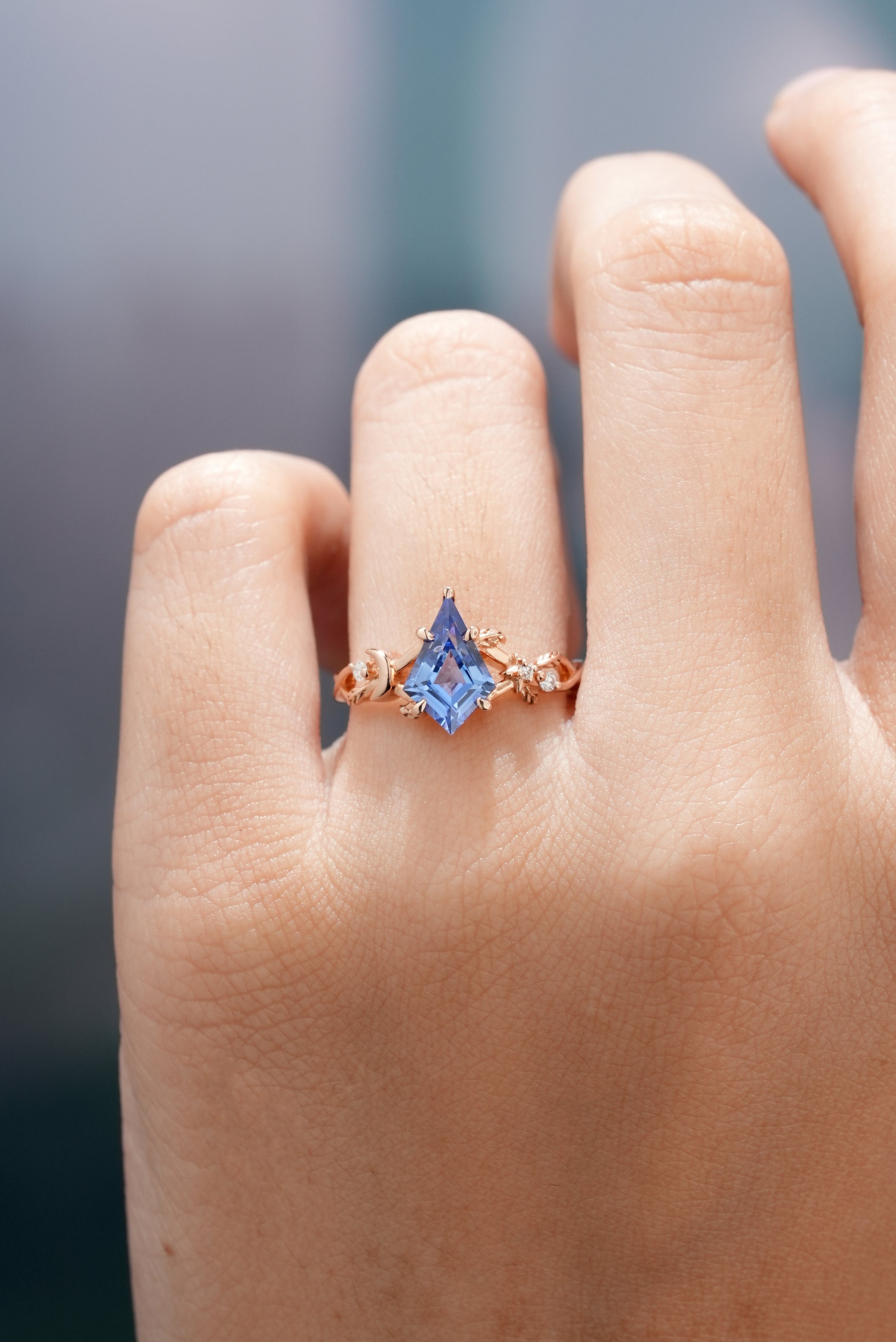 Rose gold kite cut sapphire engagement ring on a hand