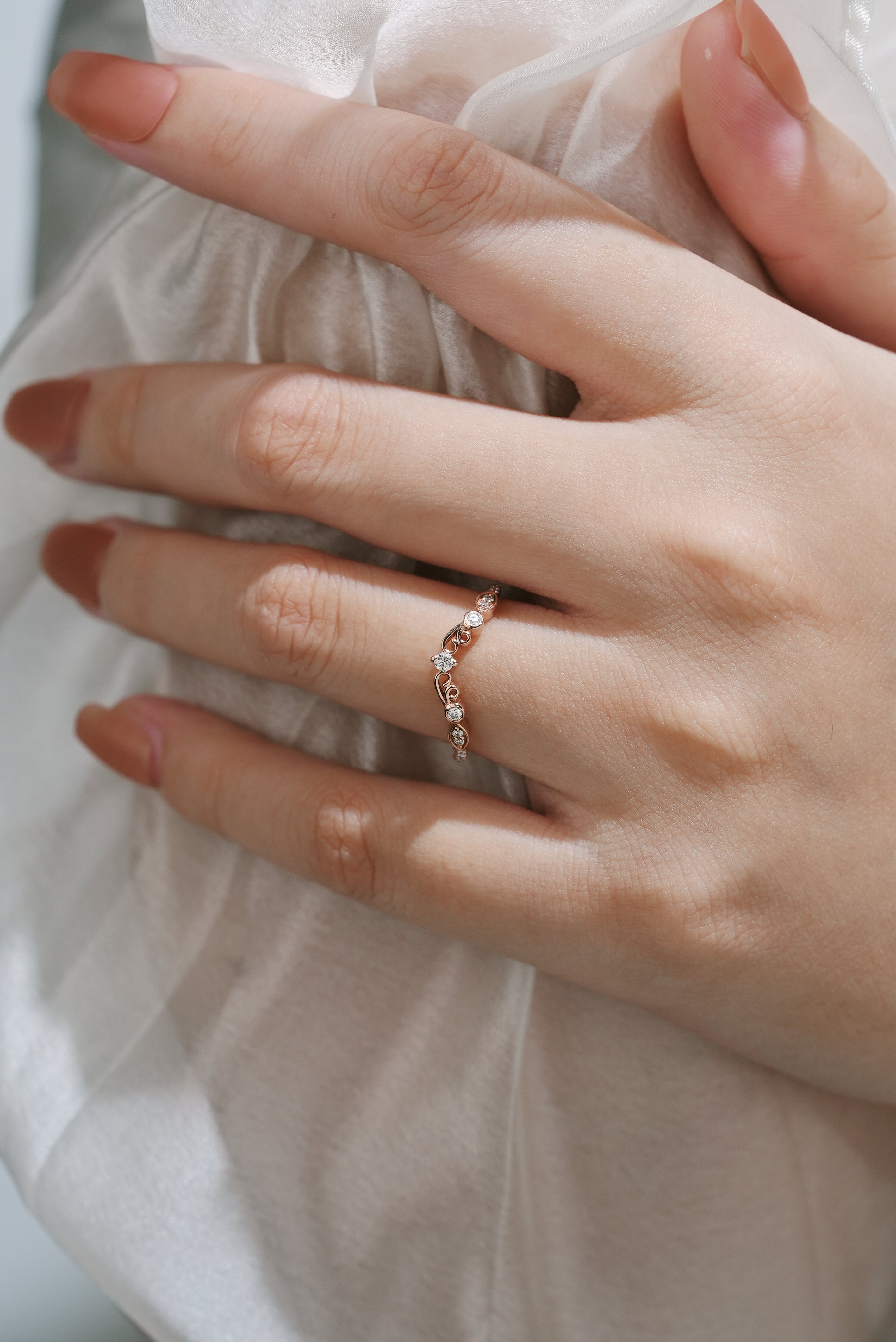 Moissanite vintage chevron wedding band in rose gold on a hand, bridal ring set