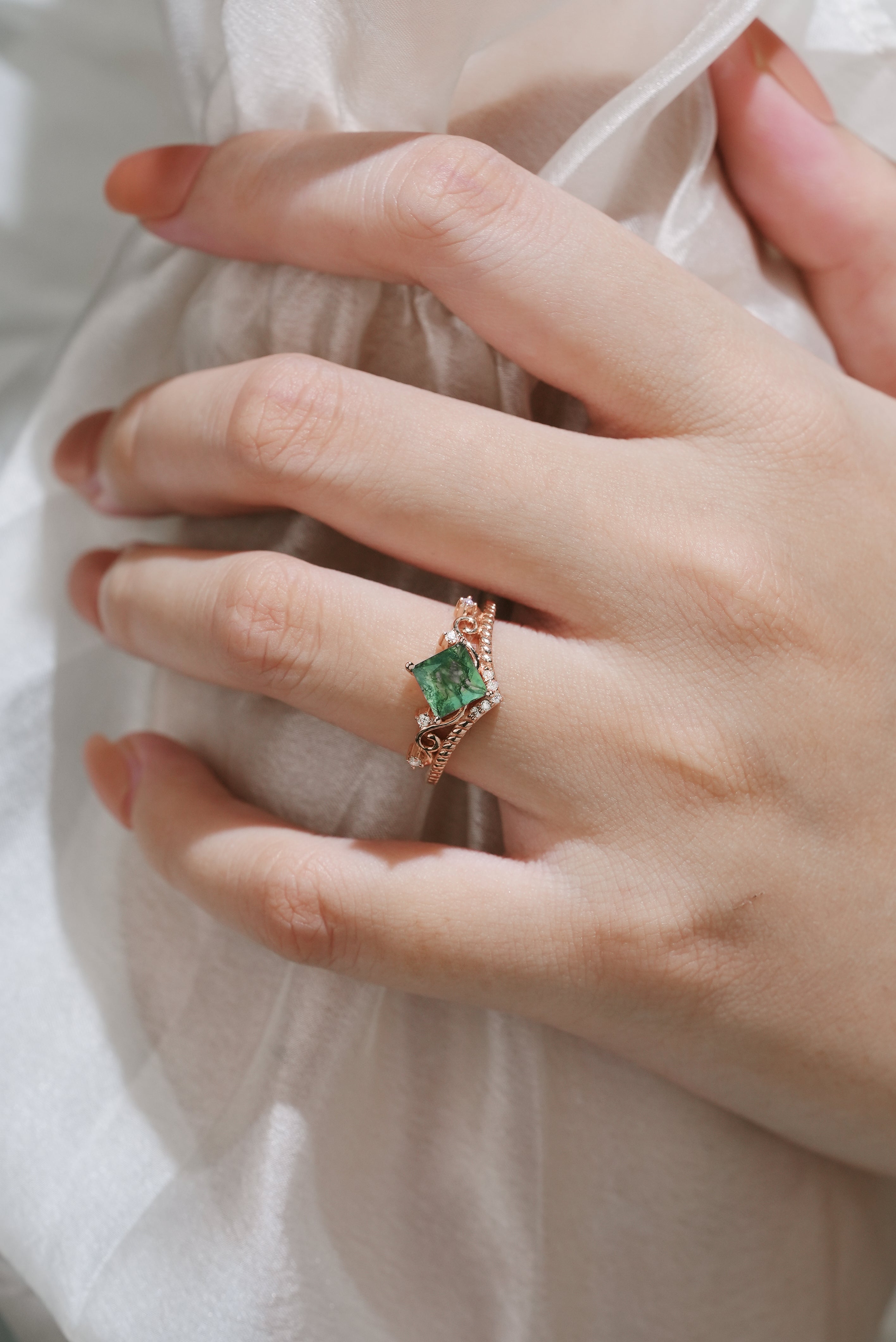 Hand wearing moss agate vintage engagement ring with princess cut
