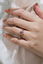 Hand wearing purple sapphire leaf engagement ring set